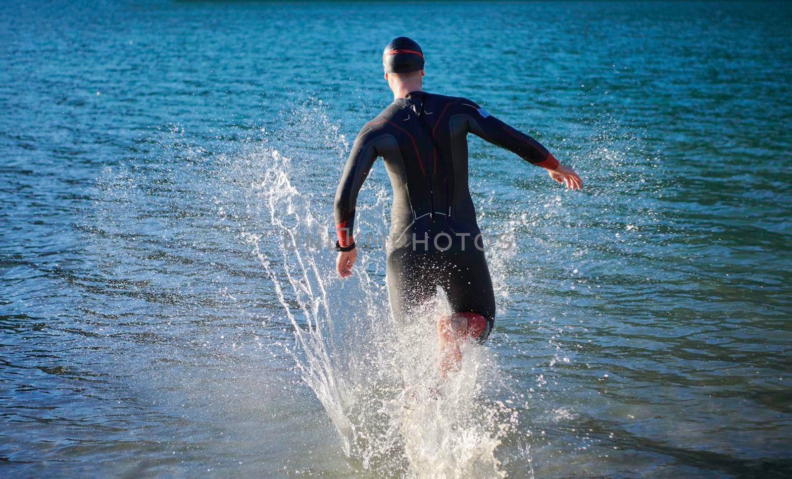 triathlon athlete starting swimming training on lake by dotshock