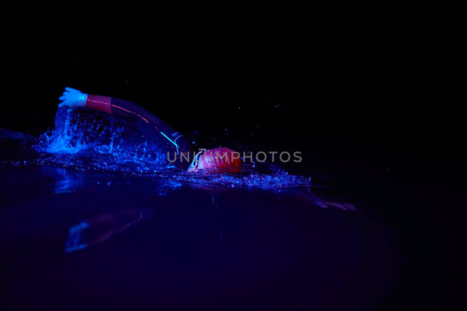 real triathlon athlete swimming in dark night by dotshock