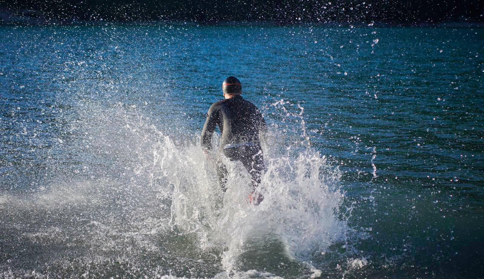 triathlon athlete start swimming training splashing water while running and jumping