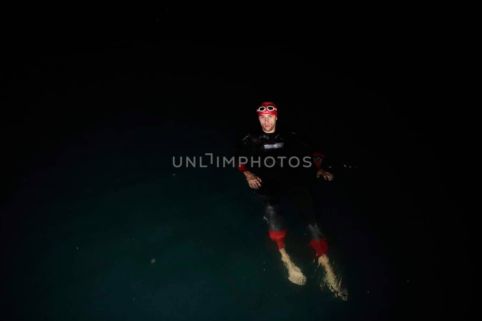 triathlon swimmer have extreme training  on dark night wearing wetsuit concept of strength and endurance