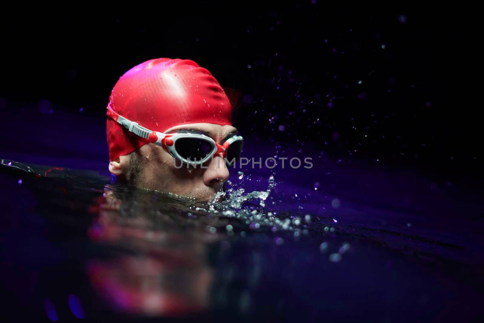 real triathlete swimmer having a break during hard training at lake on dark night