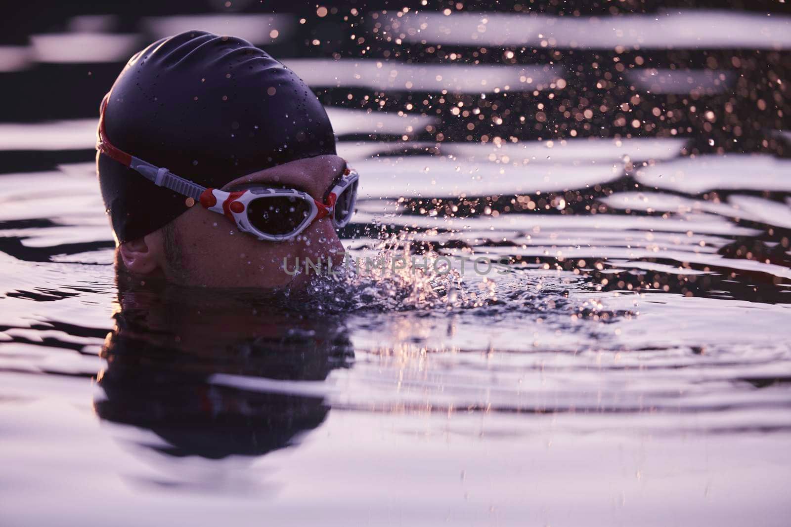 real triathlete swimmer having a break during hard training at lake on beautiful morning