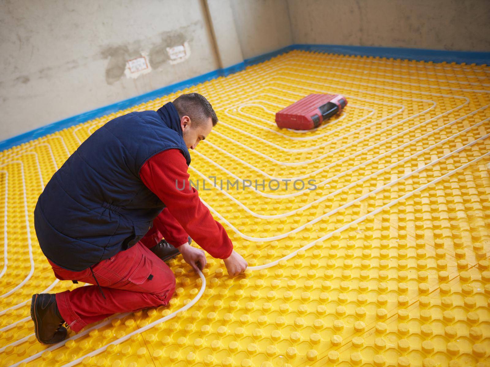 workers installing underfloor heating system by dotshock