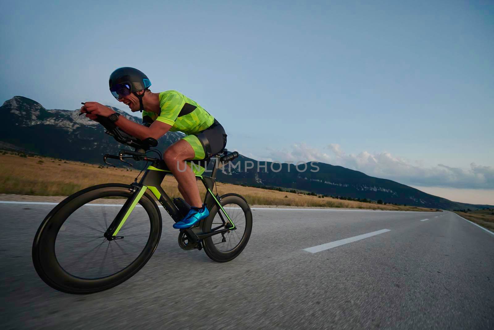 triathlon athlete riding professional racing bike at workout on curvy country road