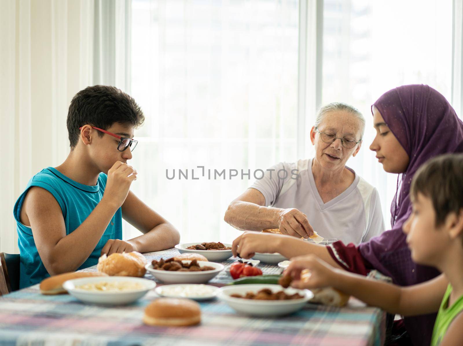 Happy family enjoying eating food in dining room together by Zurijeta