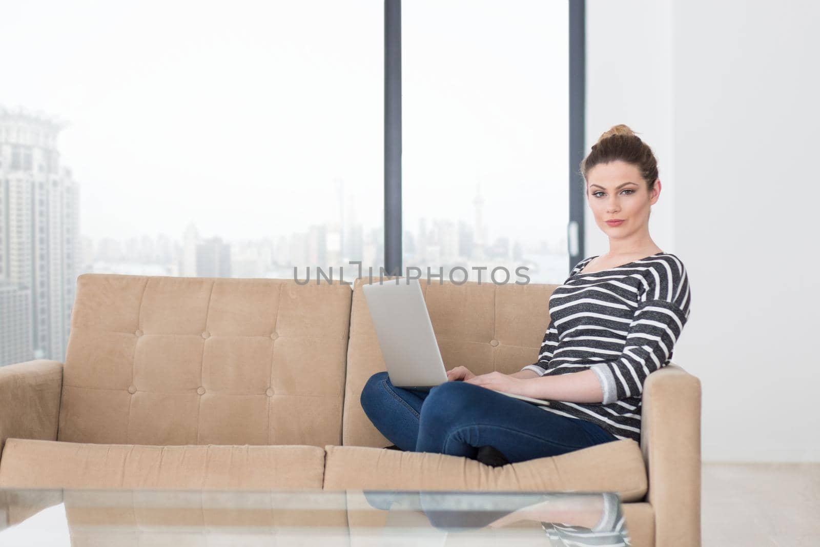 beautiful young woman on sofa at home websurfing  internet with laptop computer