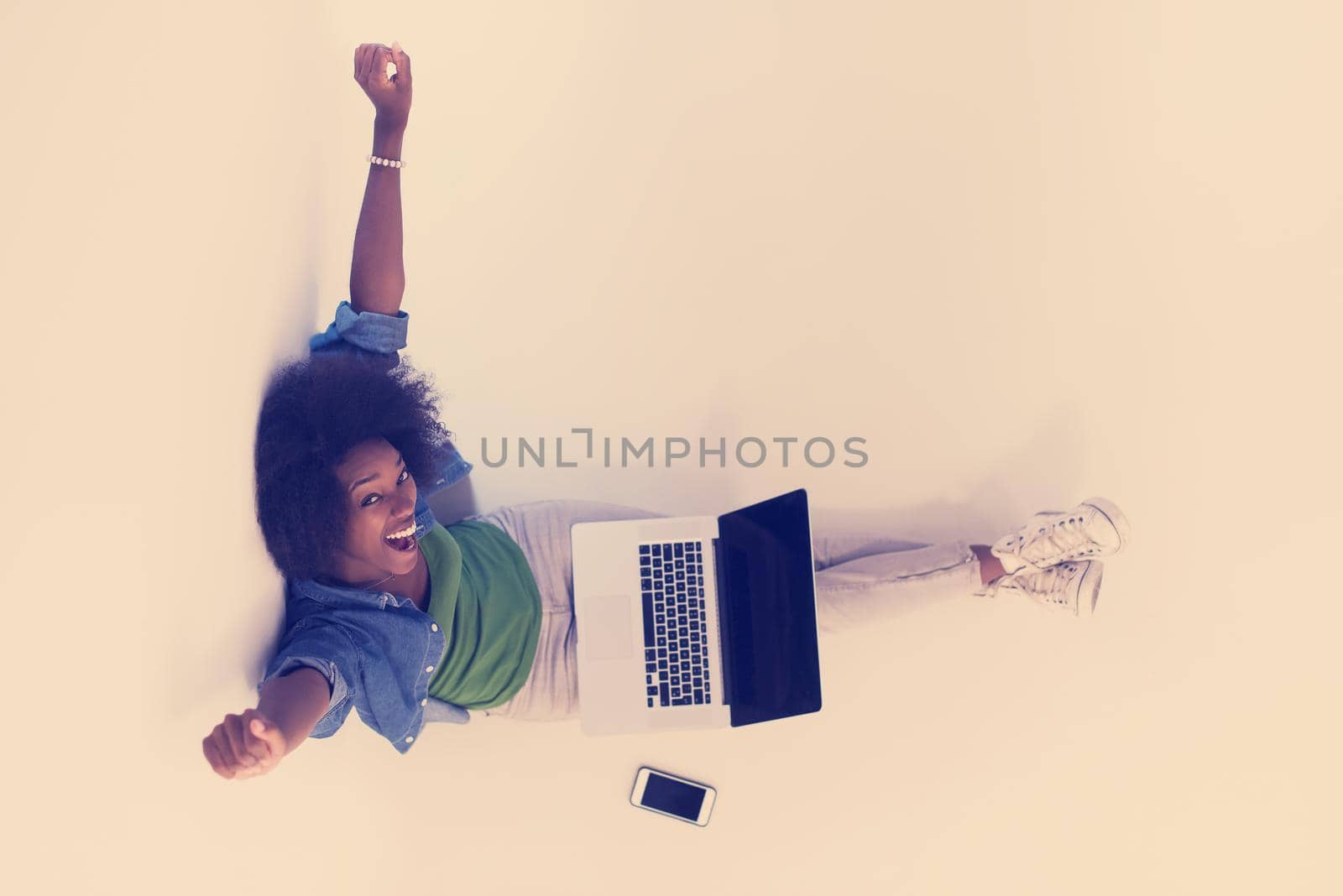 Portrait of happy young african american woman sitting on floor with laptop top view