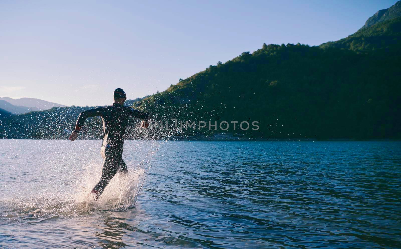 triathlon athlete start swimming training splashing water while running and jumping