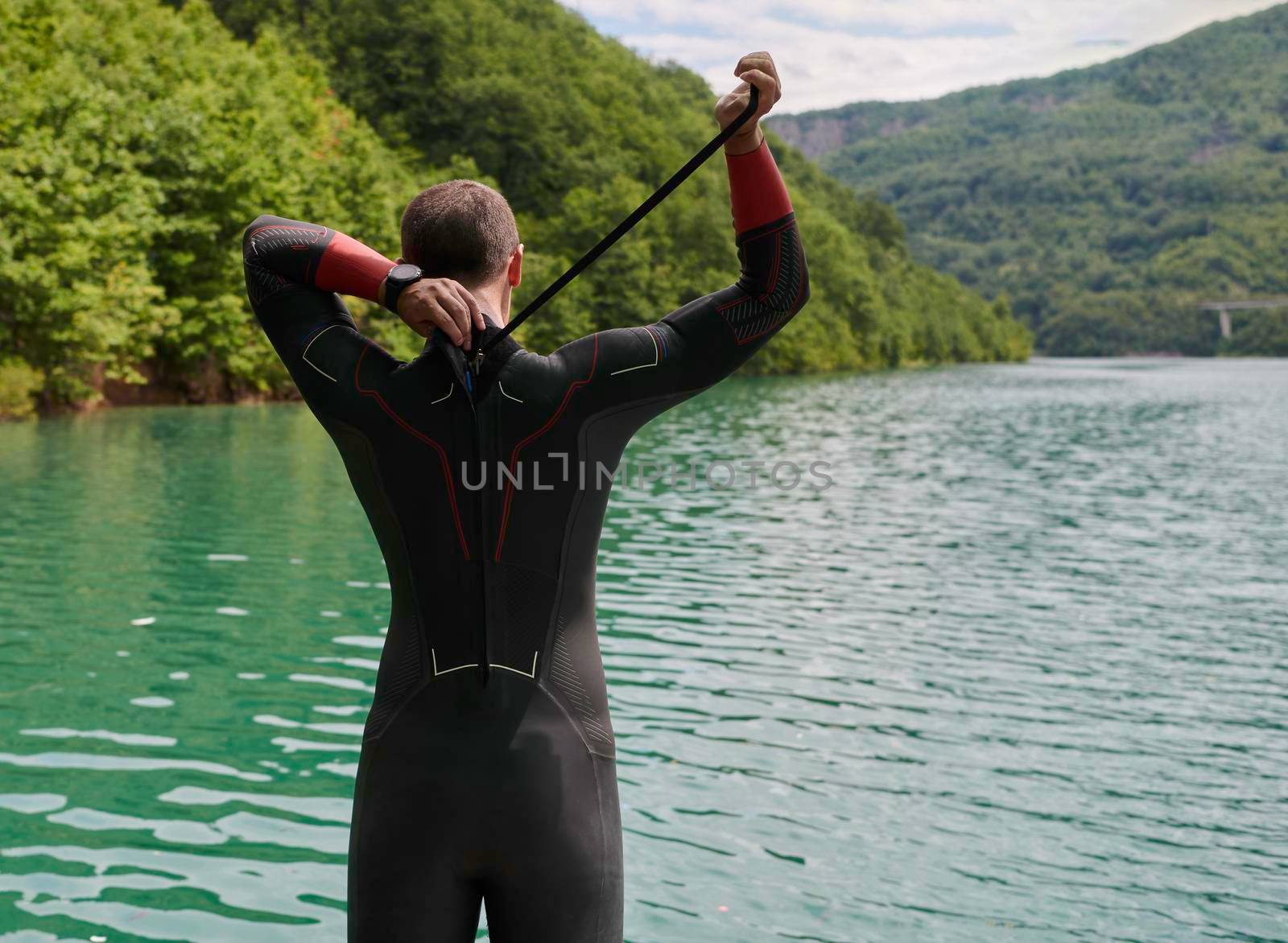 triathlon athlete getting ready and prepare goggles hat and  wetsuit for swimming training on lake