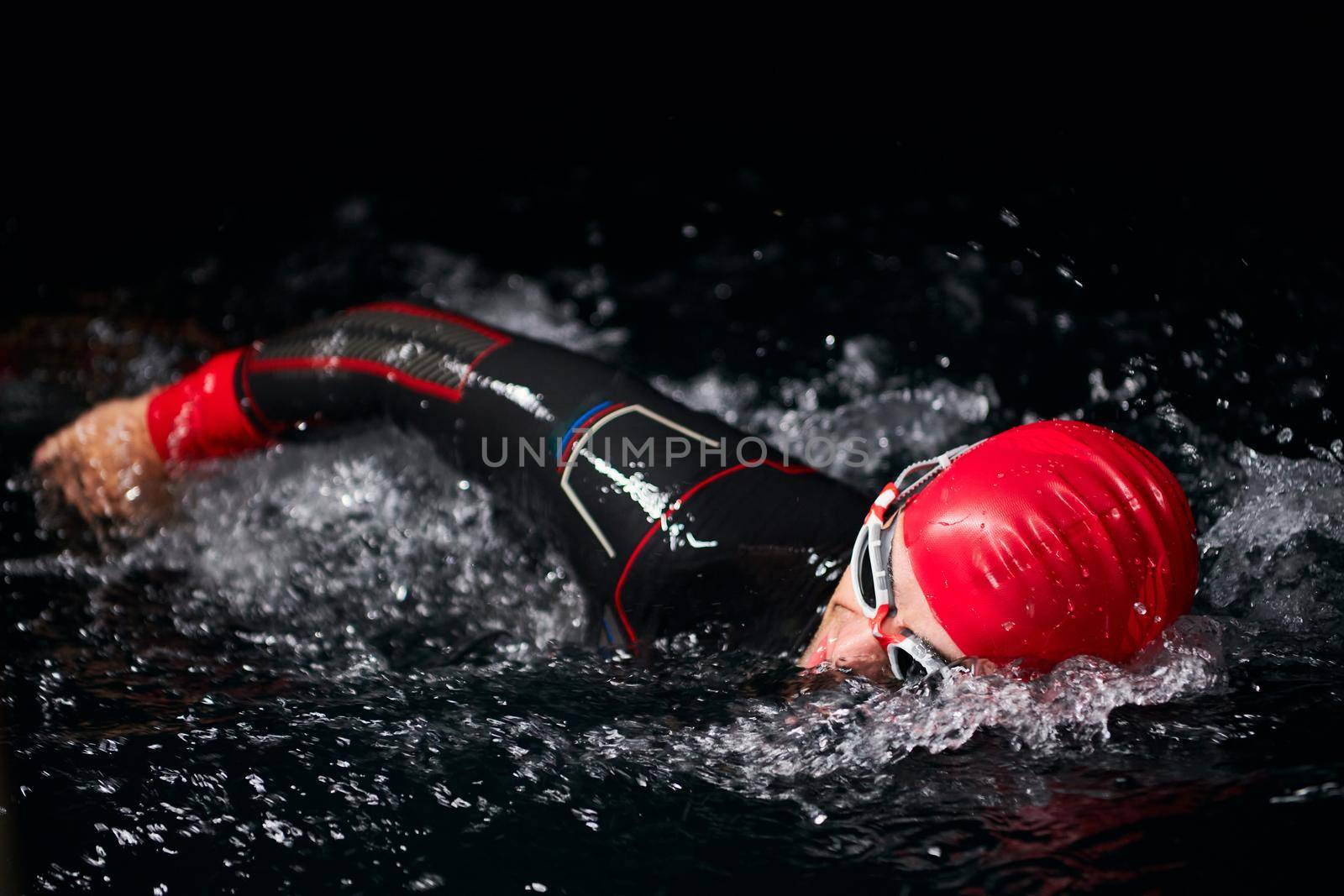 triathlon swimmer have extreme training  on dark night wearing wetsuit concept of strength and endurance