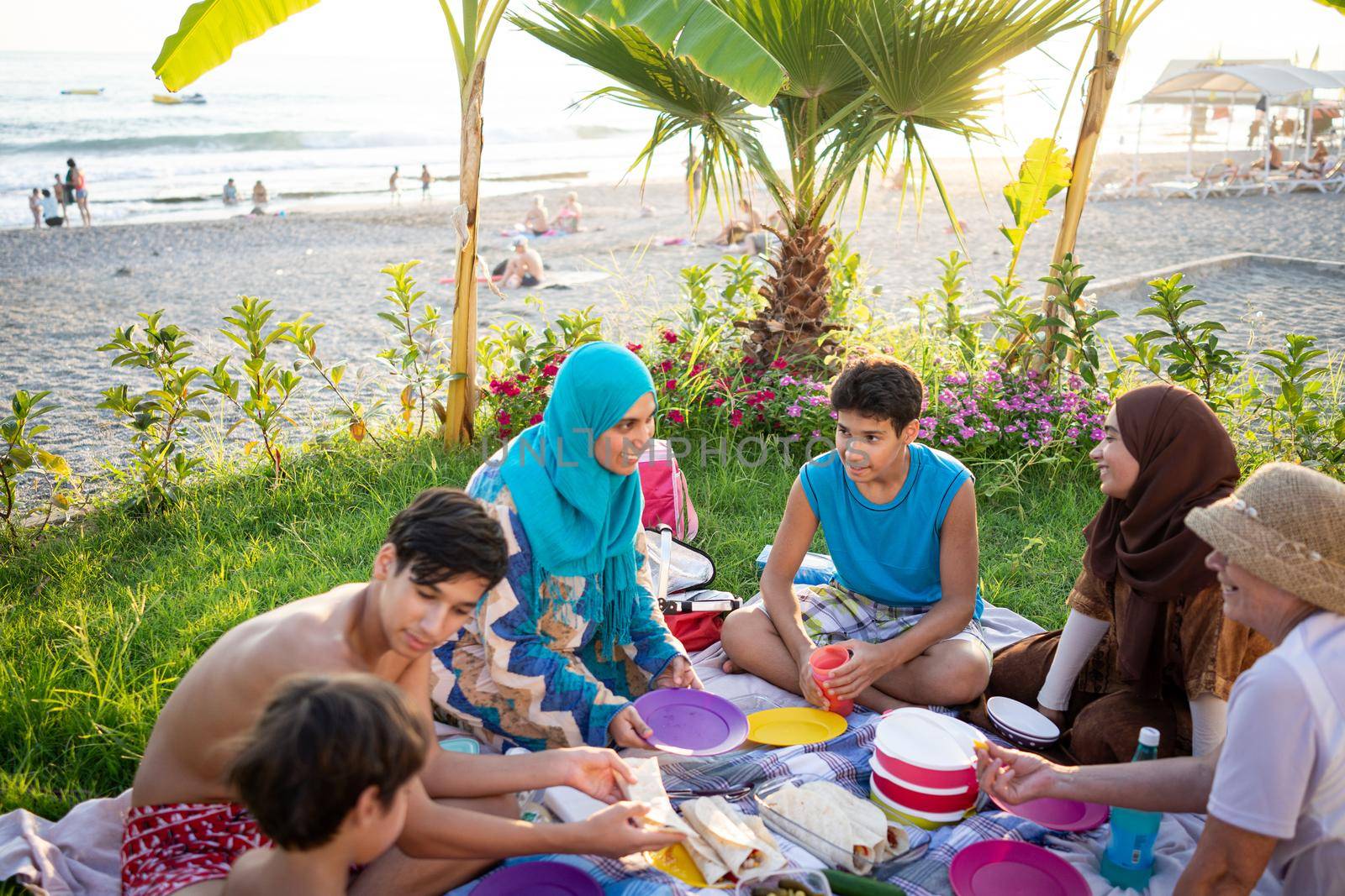 Happy family enjoying picnic on beach near sea