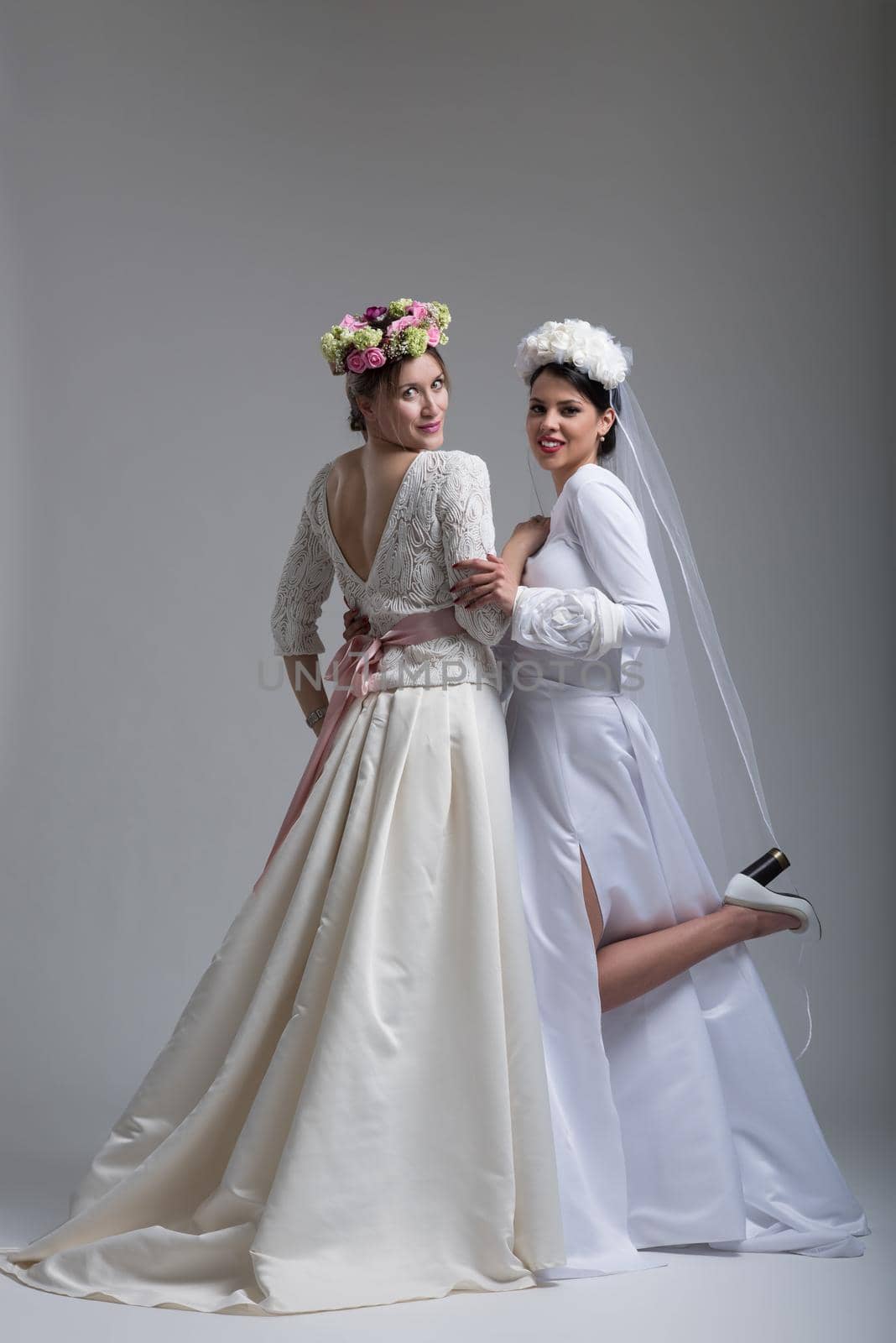 Portrait of two beautiful young bride in wedding dresses isolated on a white background