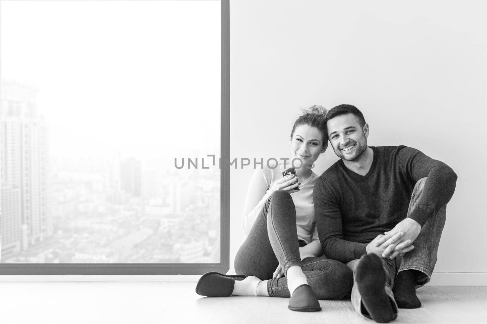 happy young couple sitting near window at home on cold winter day