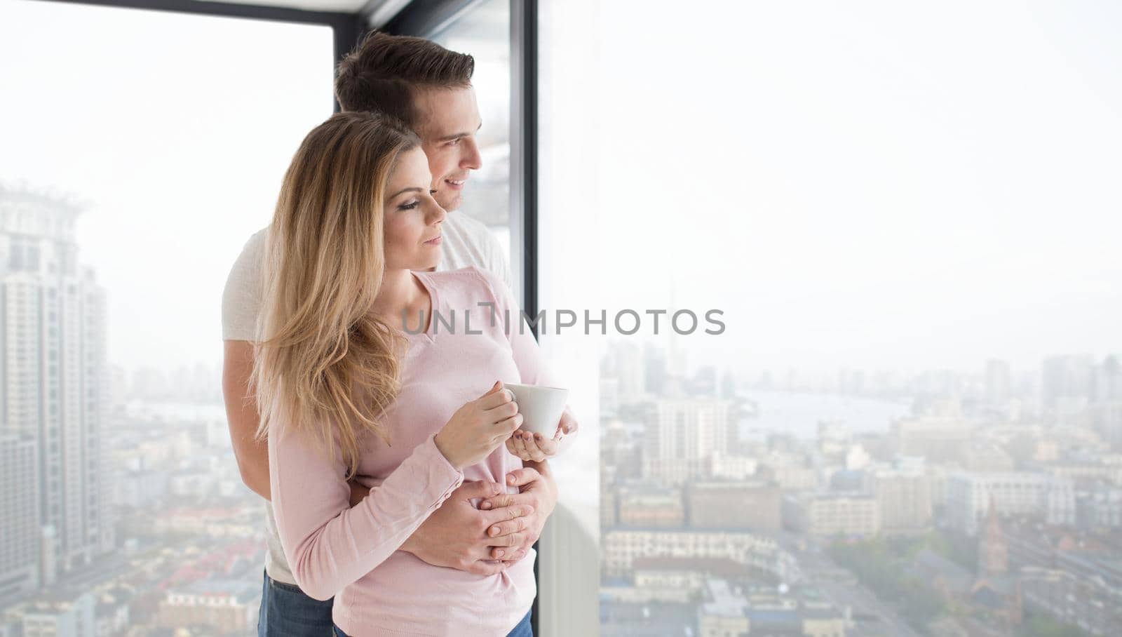 romantic happy young couple enjoying morning coffee by the window on cold winter day at home