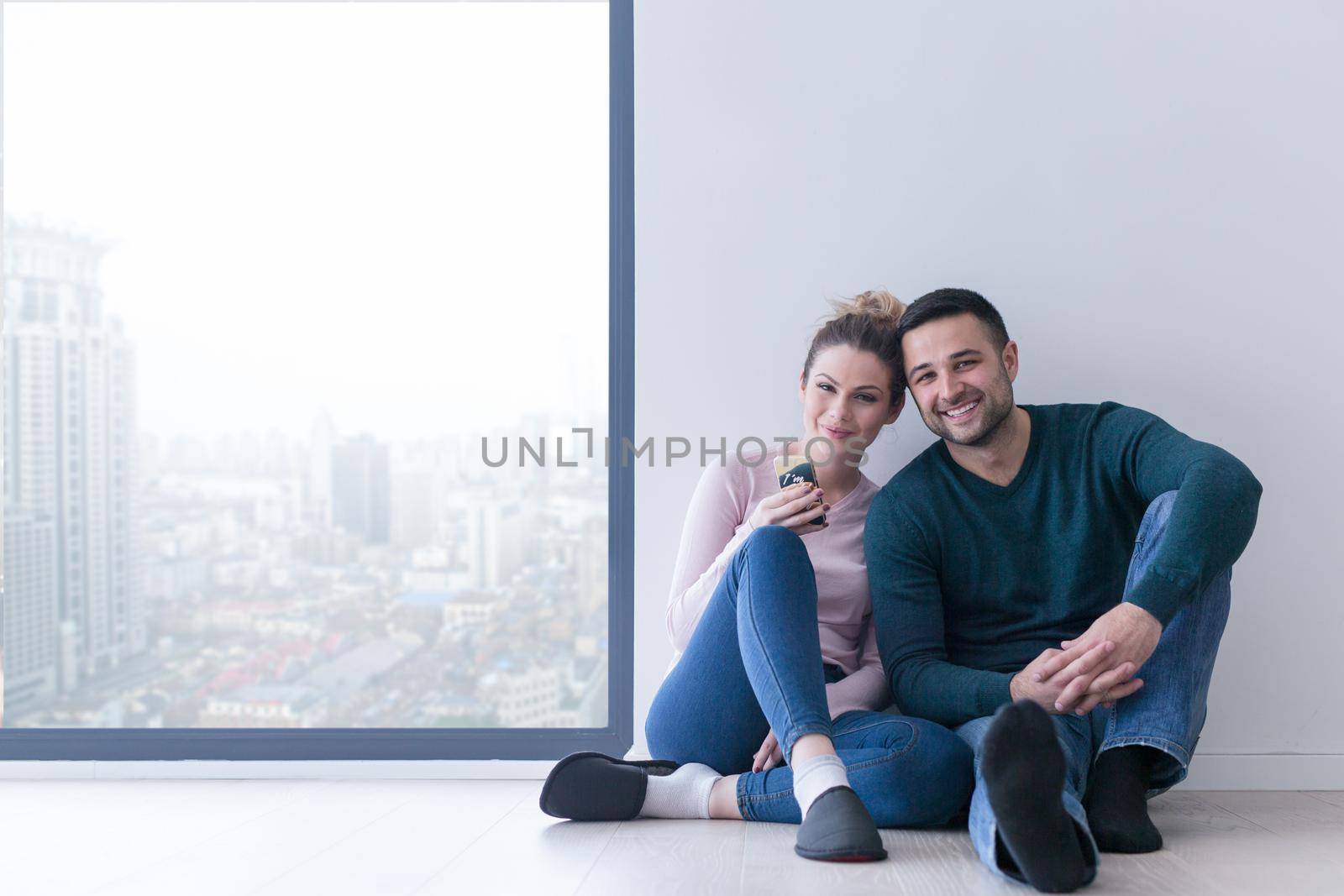 happy young couple sitting near window at home on cold winter day