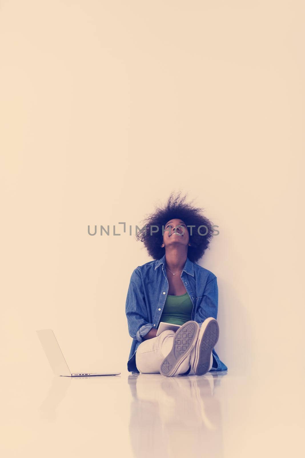 african american woman sitting on floor with laptop by dotshock