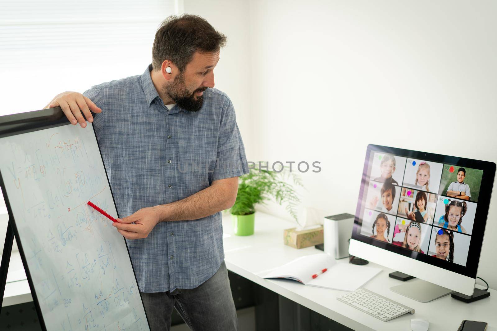 Male teacher having online conference with school children working at home