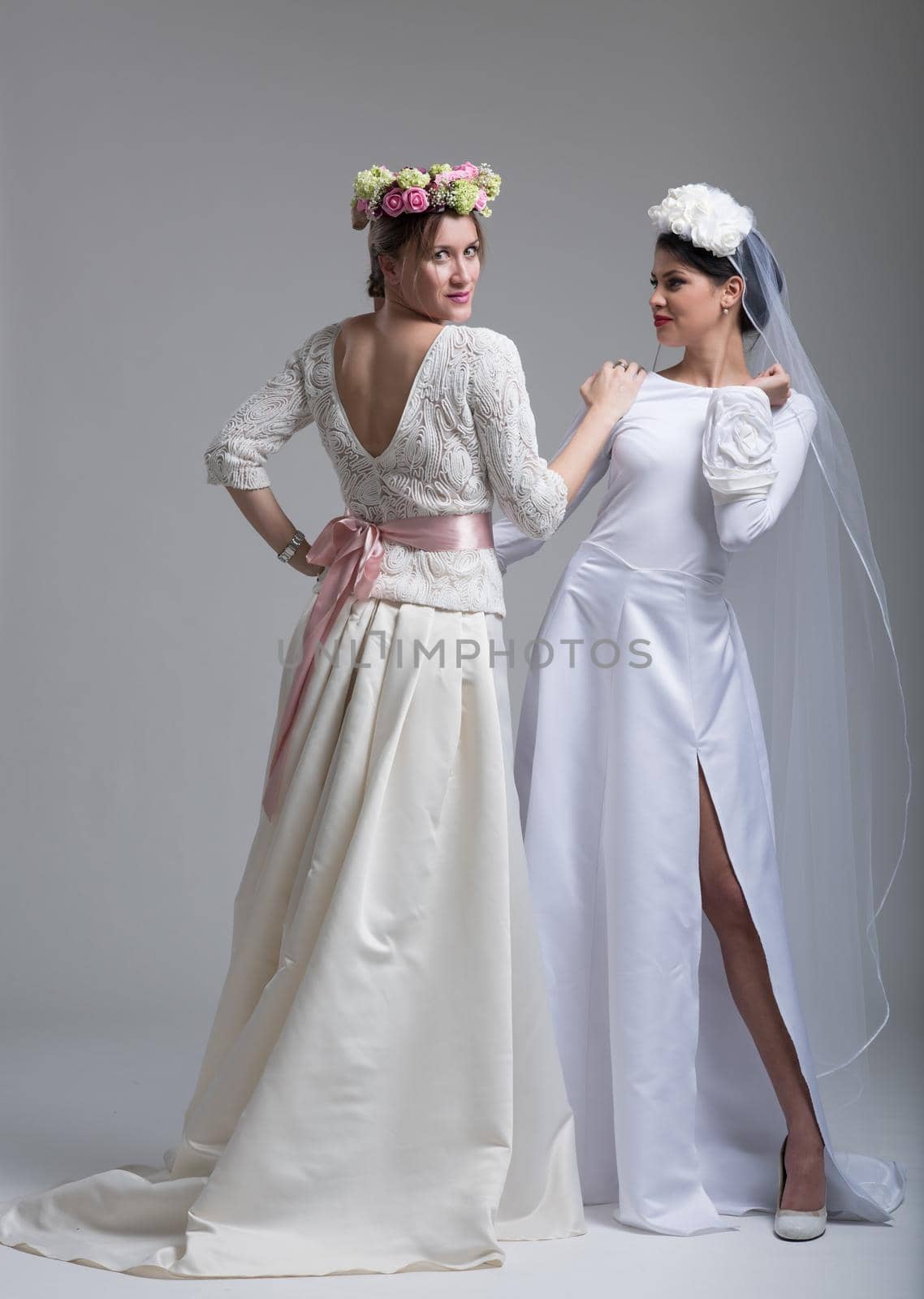 Portrait of two beautiful young bride in wedding dresses isolated on a white background