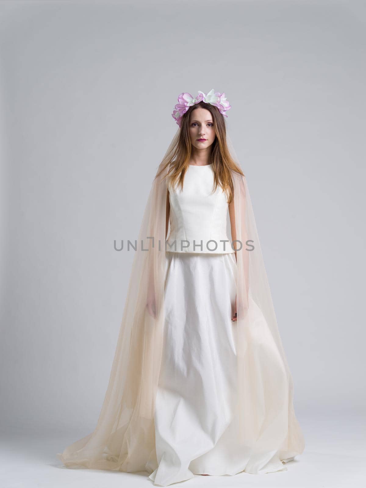 Portrait of beautiful young bride in a wedding dress with a veil isolated on a white background