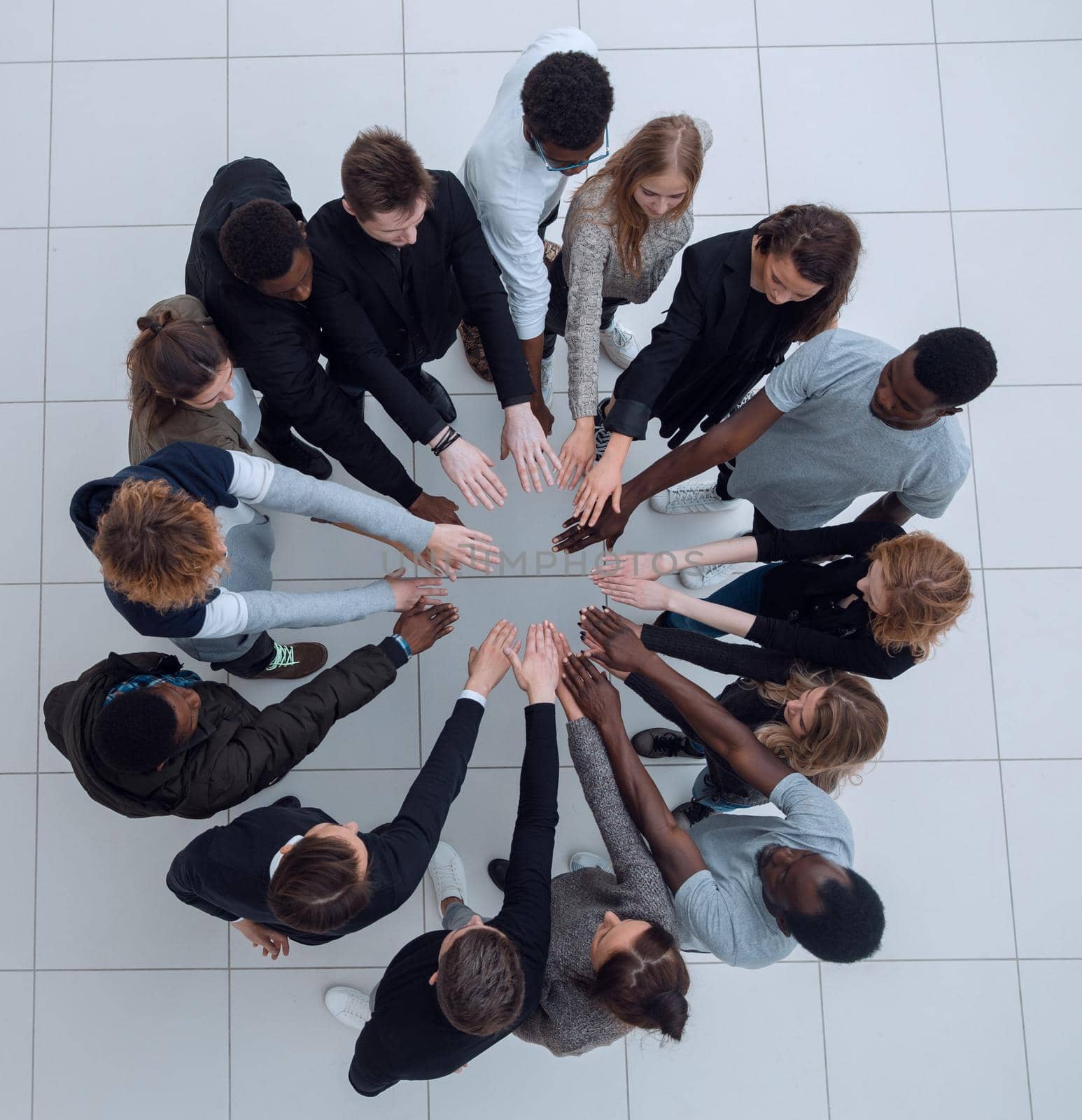 group of young successful people stands around hands together by asdf