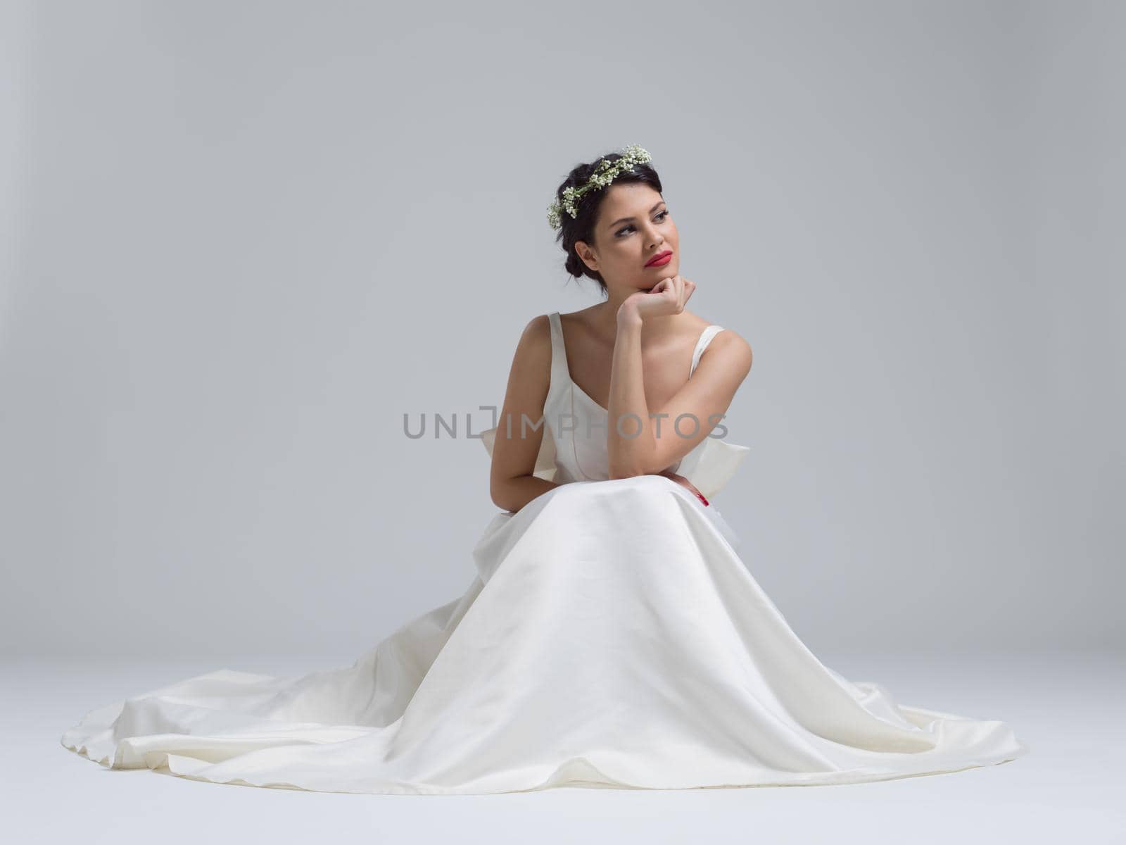 Beautiful young bride sitting in a wedding dress isolated on a white background