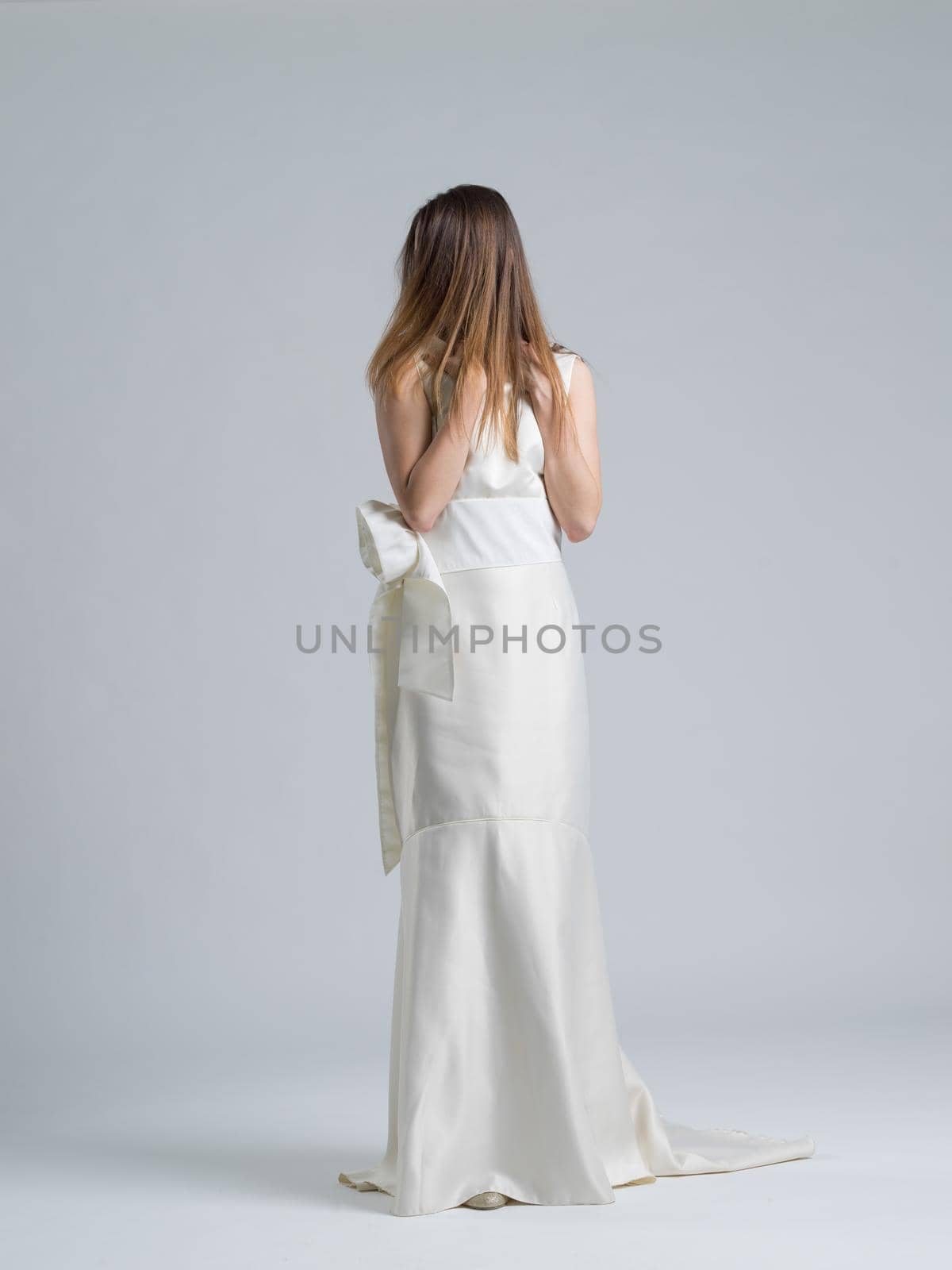 Rear view of a beautiful young bride in a wedding dress isolated on a white background