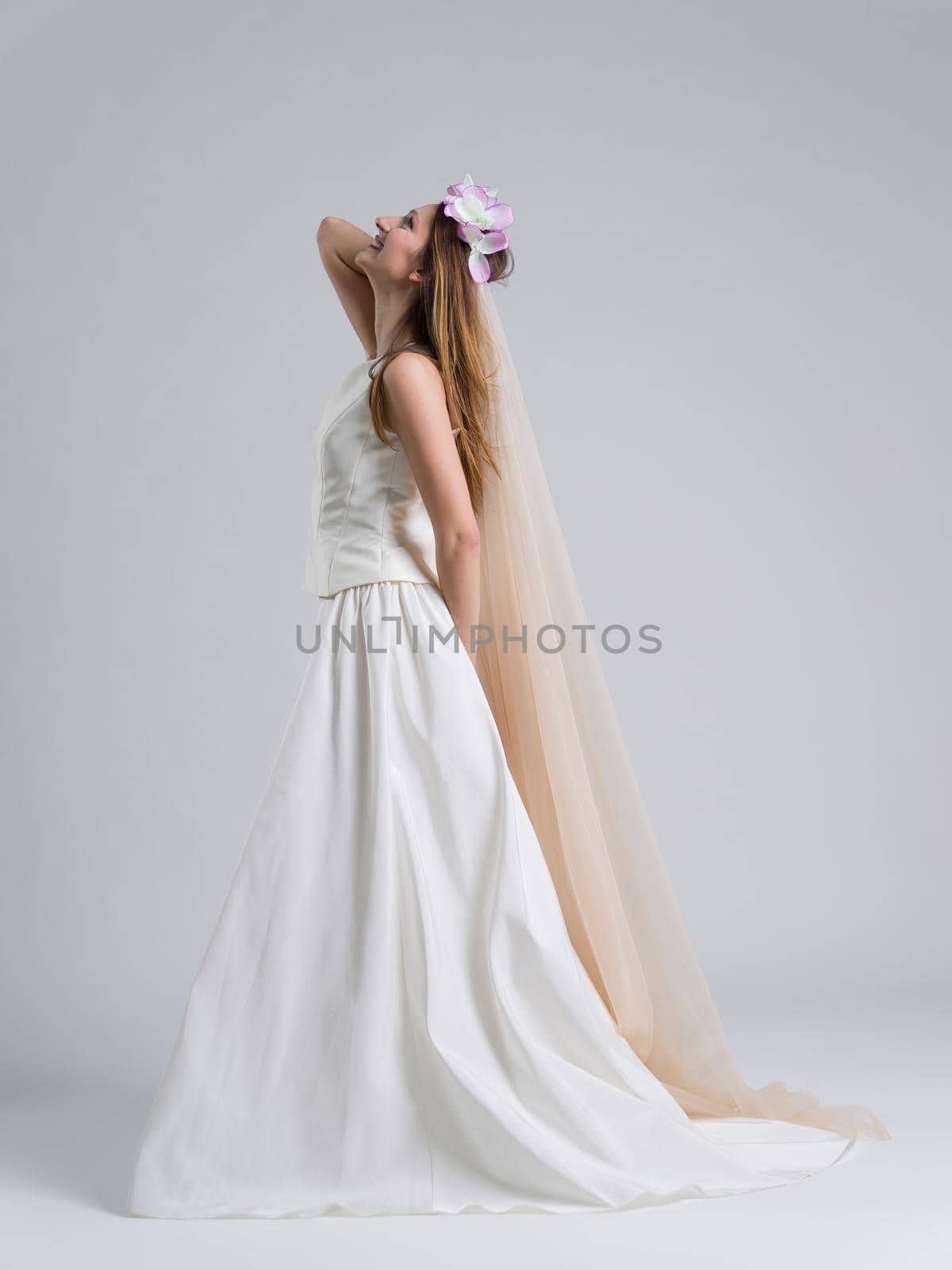 Portrait of beautiful young bride in a wedding dress with a veil isolated on a white background