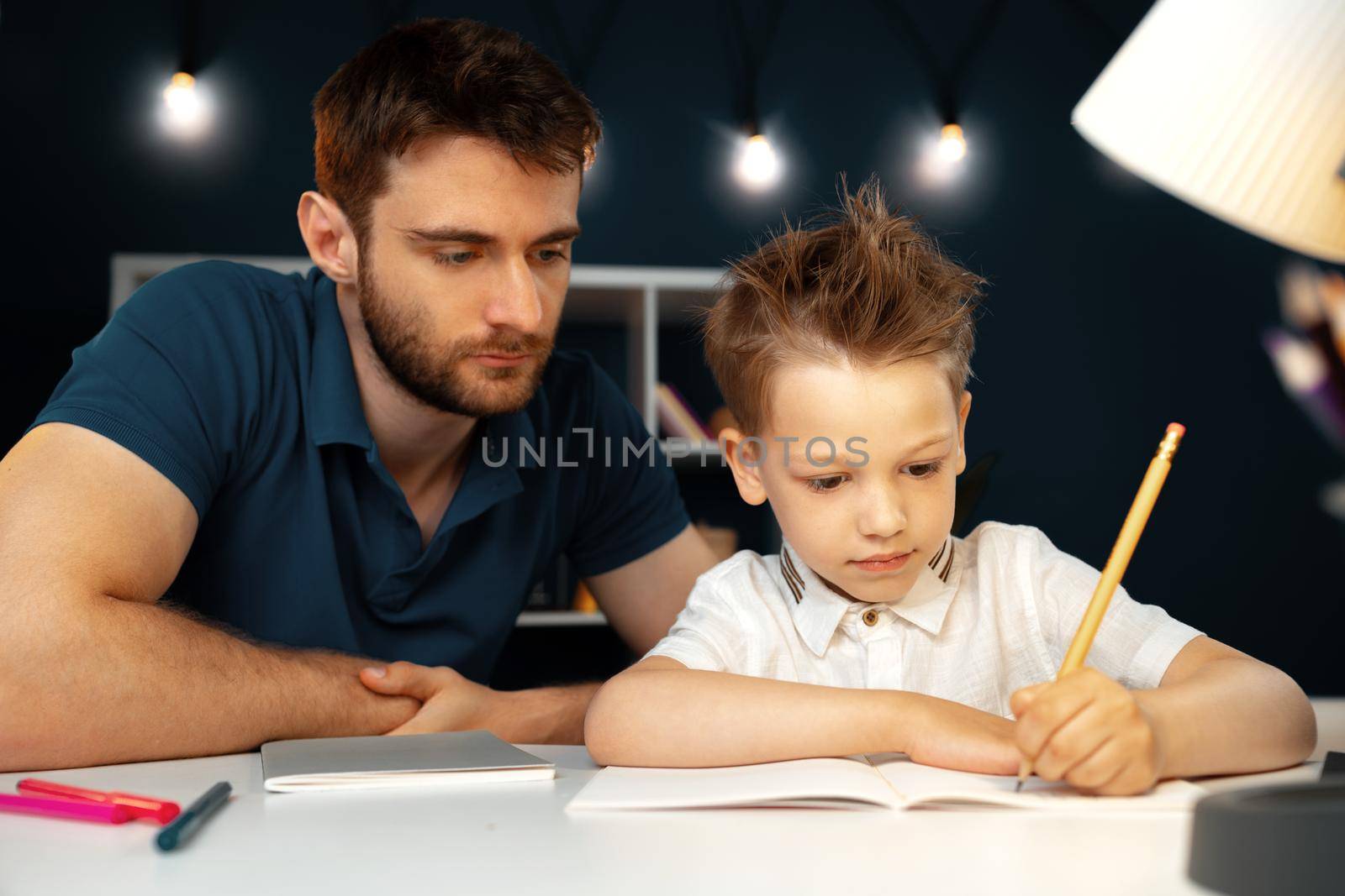 Dad and son doing school homework together sitting at the table