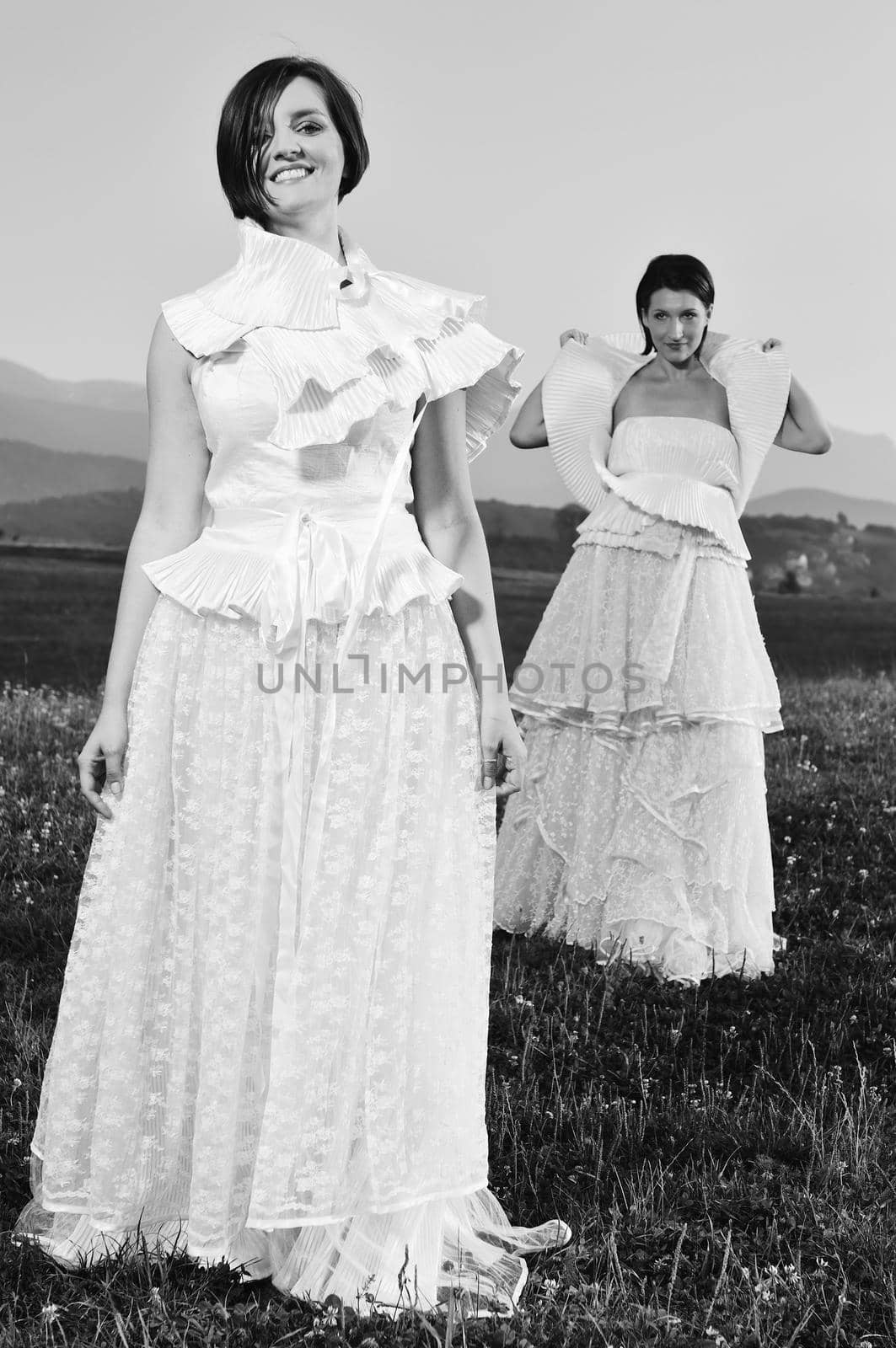 group of bride run on meadow at sunset after wedding party