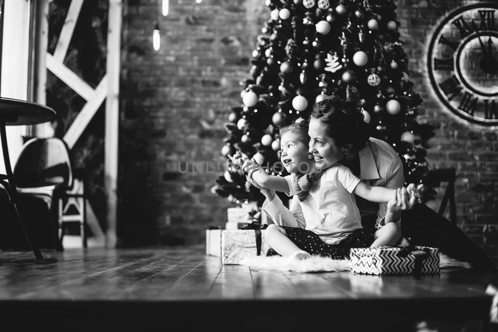 mom plays with her daughter, sitting near the Christmas tree . the concept of Christmas
