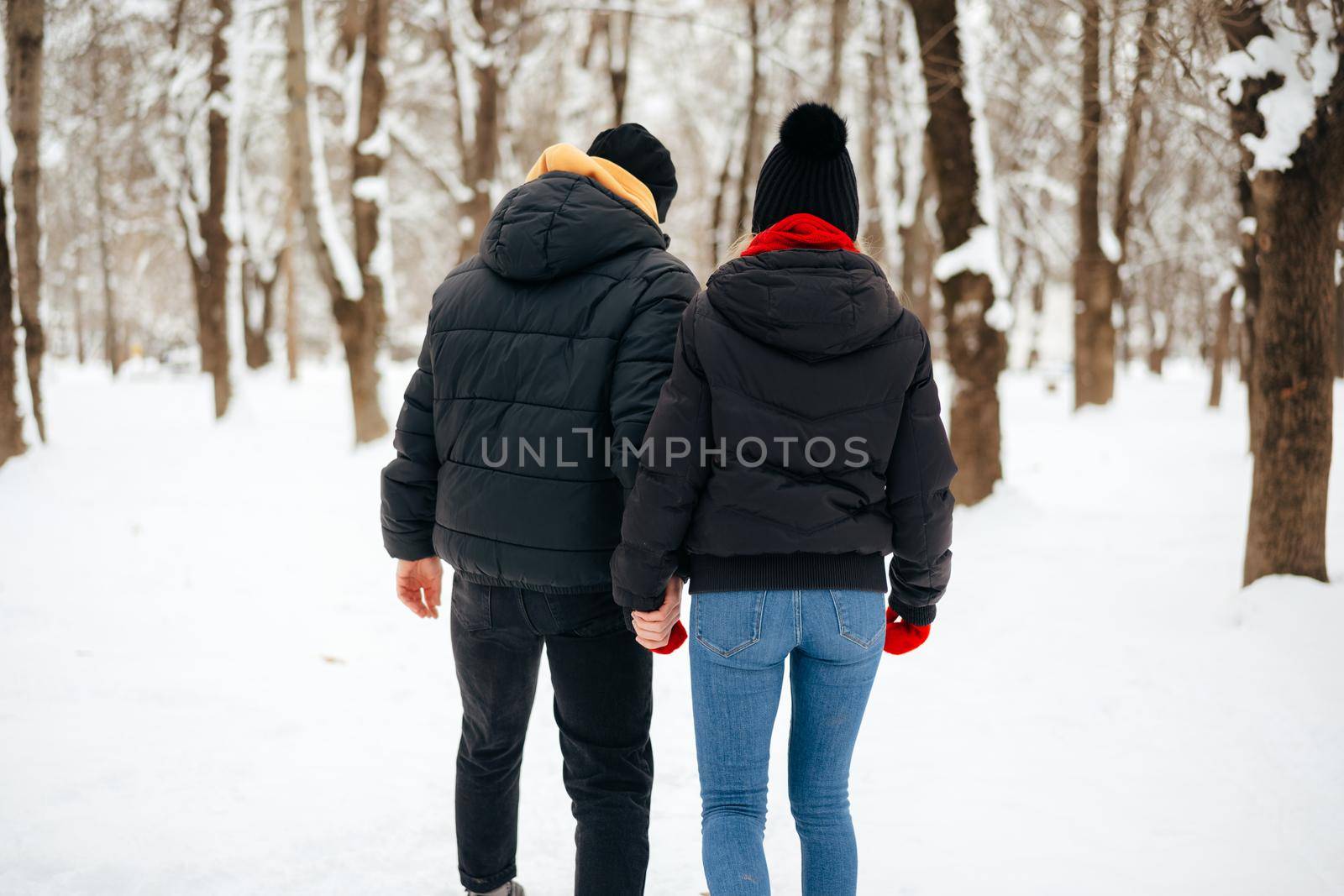 Young happy smiling couple in love having a walk in a winter park