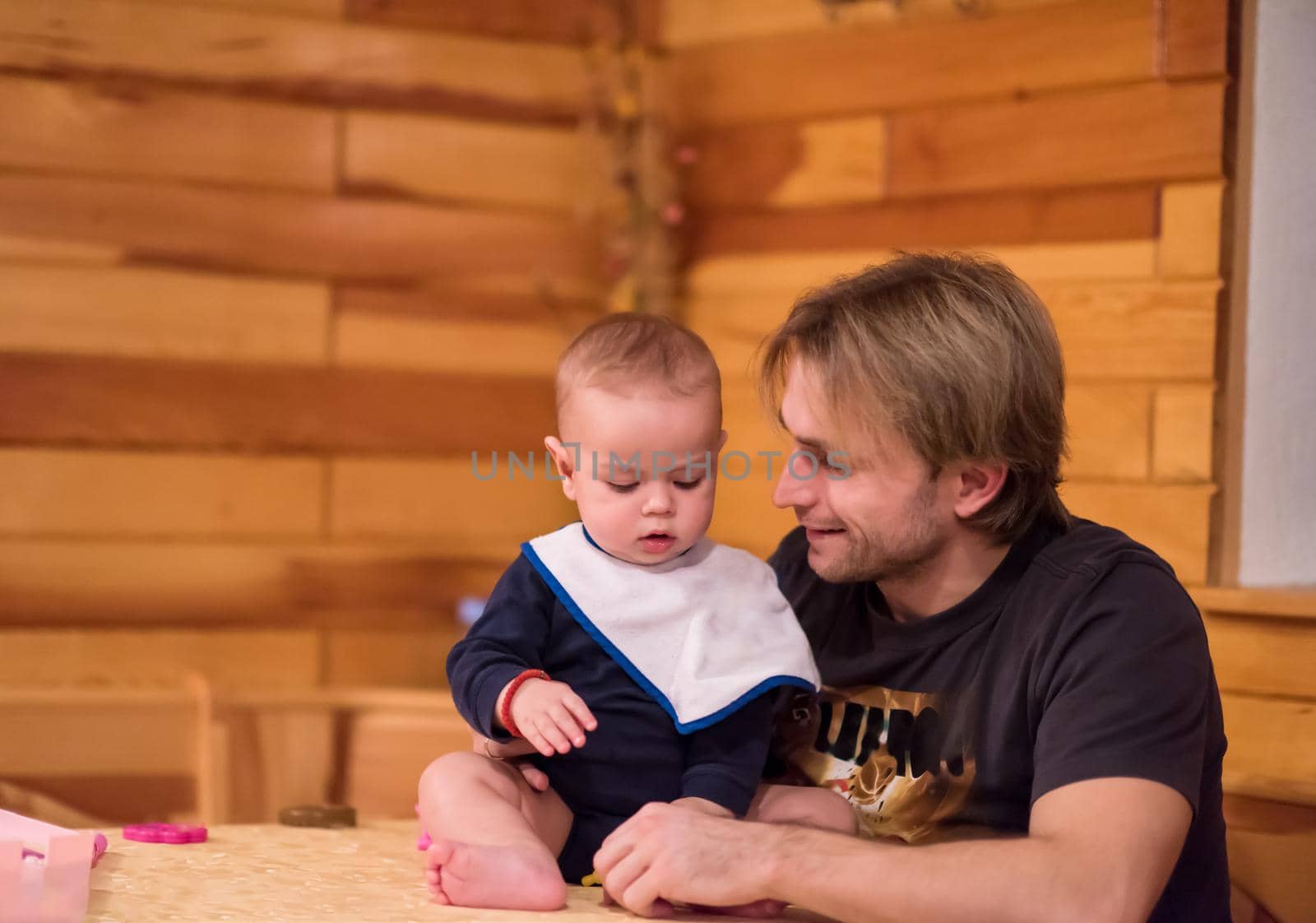 Father and son happy moments  Portrait of young father and his cute baby son playing together on table while spending time together at home