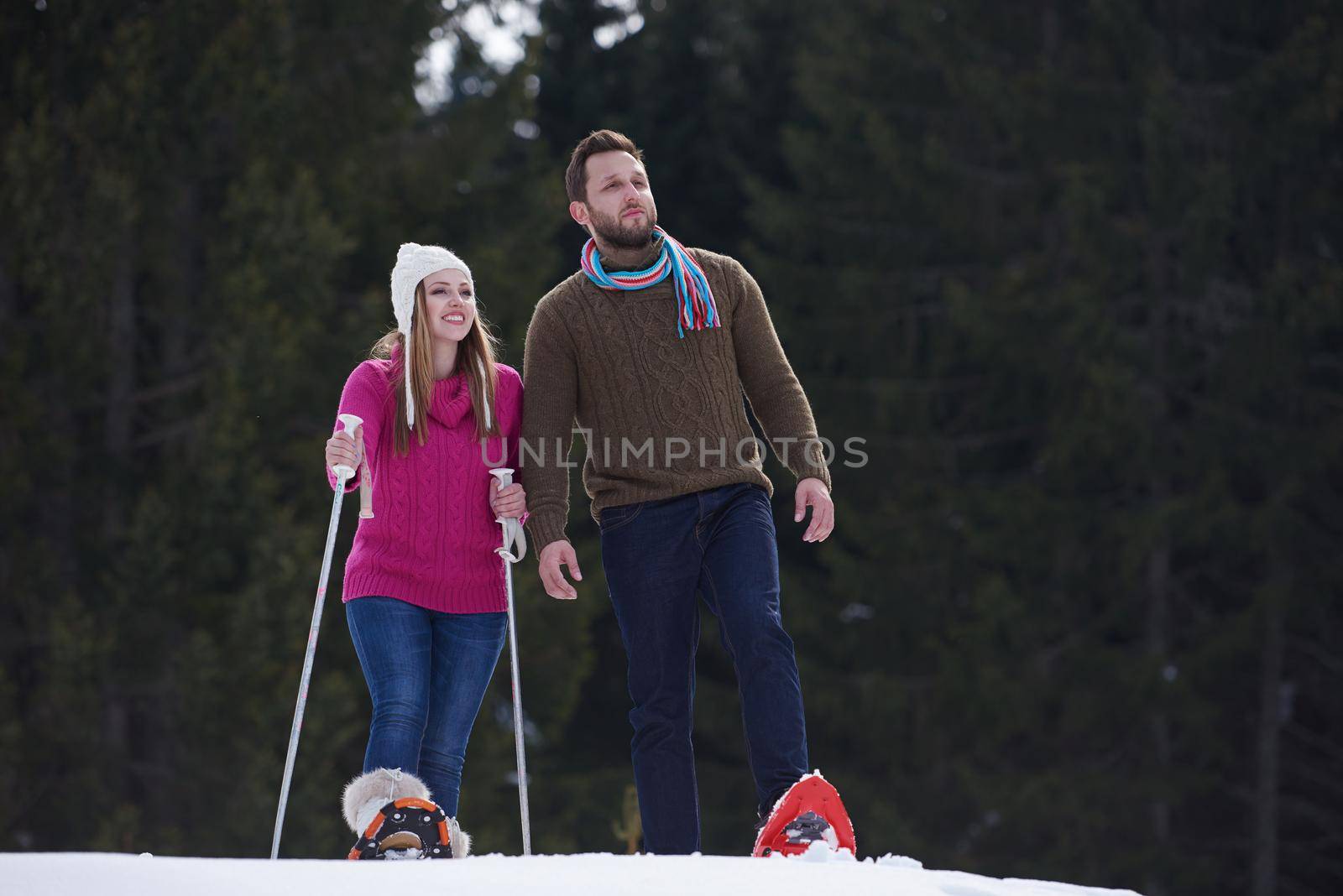 happy young  couple having fun and walking in snow shoes outdoor in nature at beautiful winter day. Health sport and relaxation