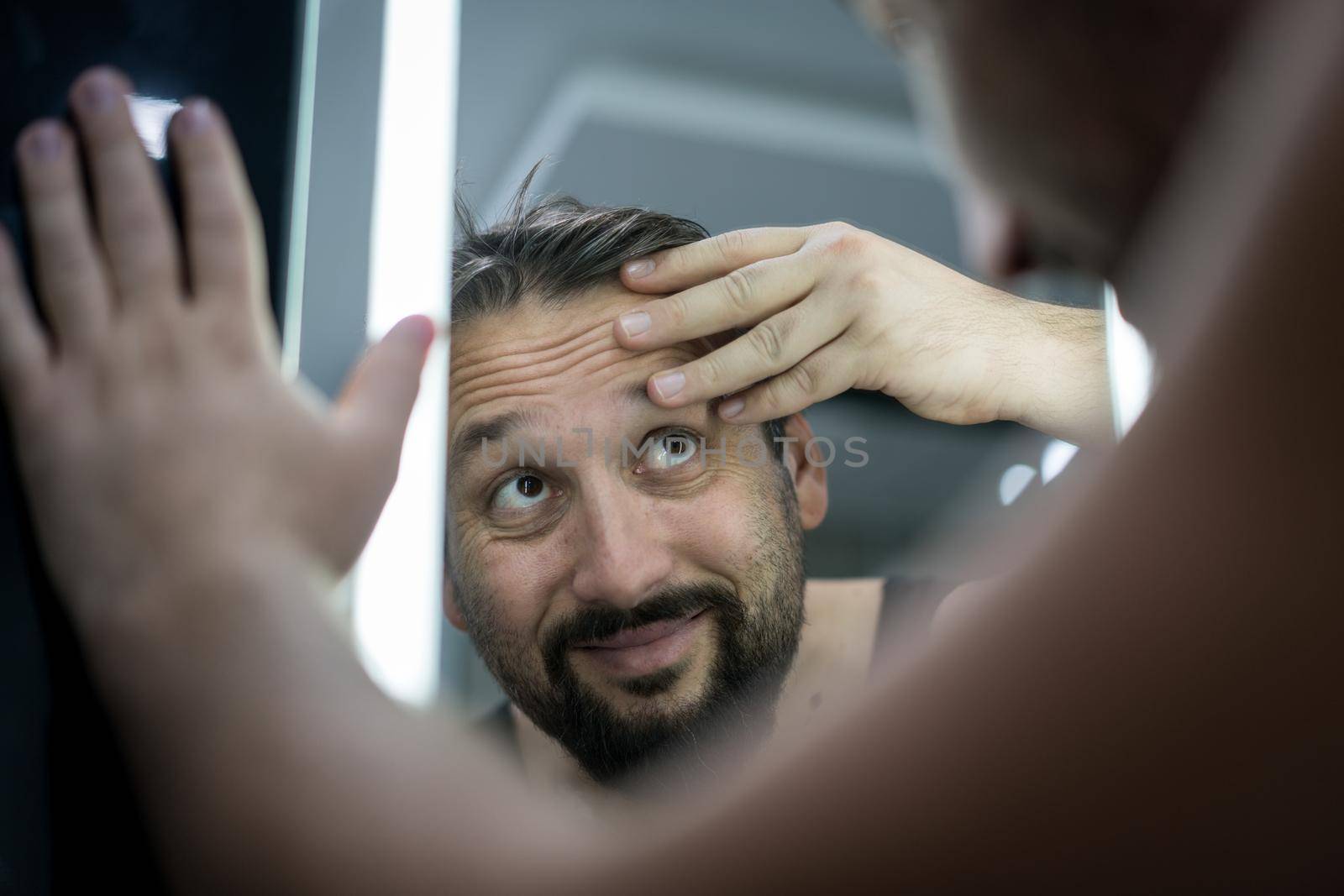 Man in front of mirror checking hair and skin