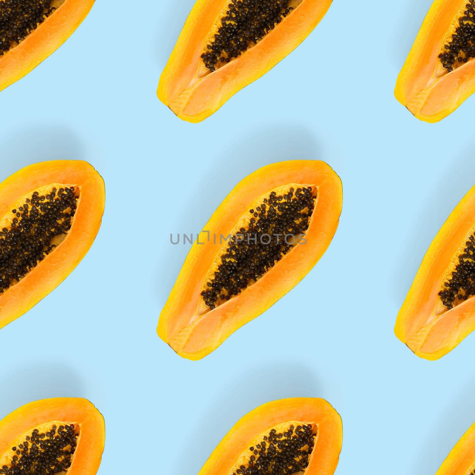 Fresh ripe papaya seamless pattern on blue background. Tropical abstract background. Top view. Creative design, minimal flat lay concept. Trend tropical fruit food background pattern