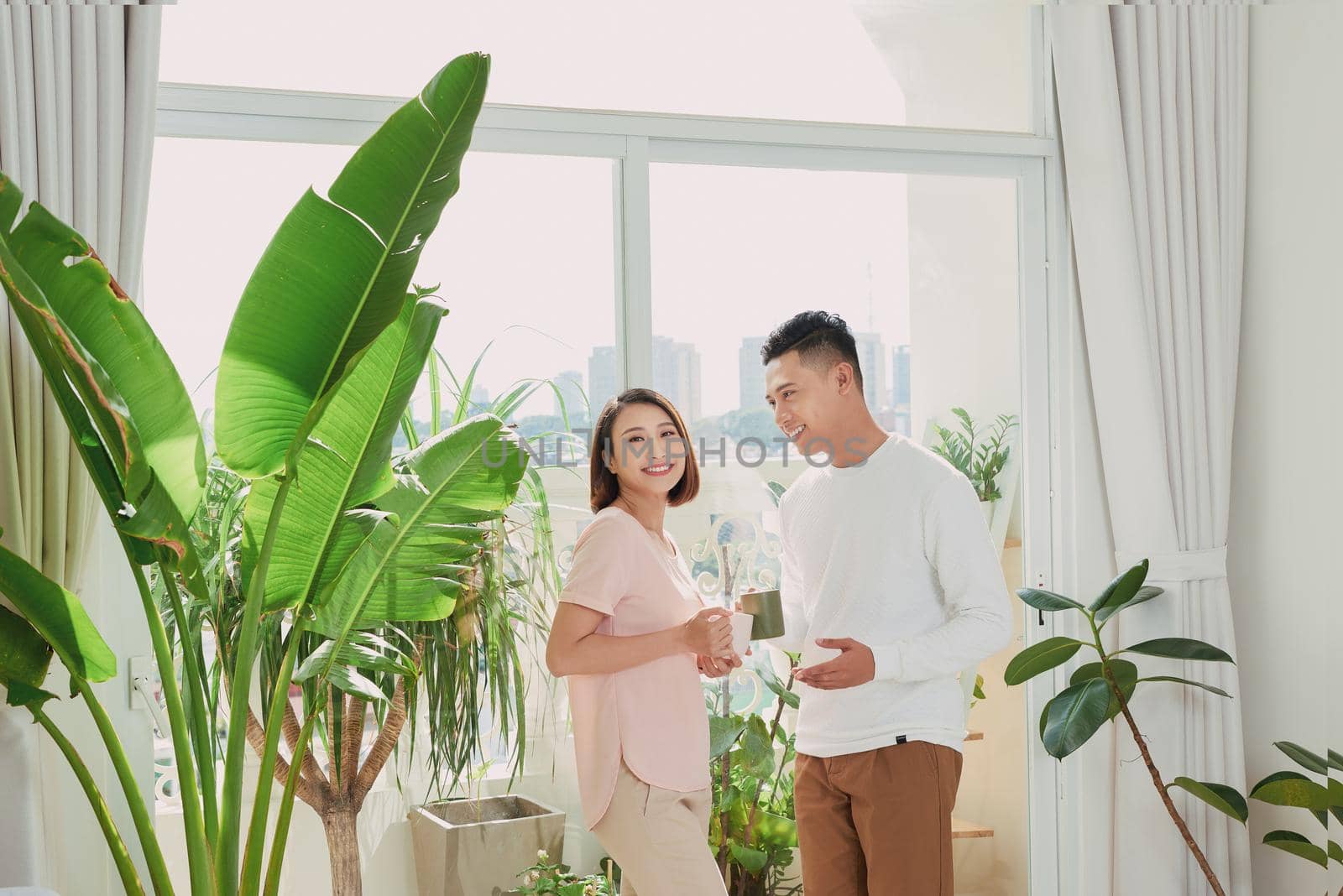 romantic happy young couple enjoying morning coffee by the window on bright day at home