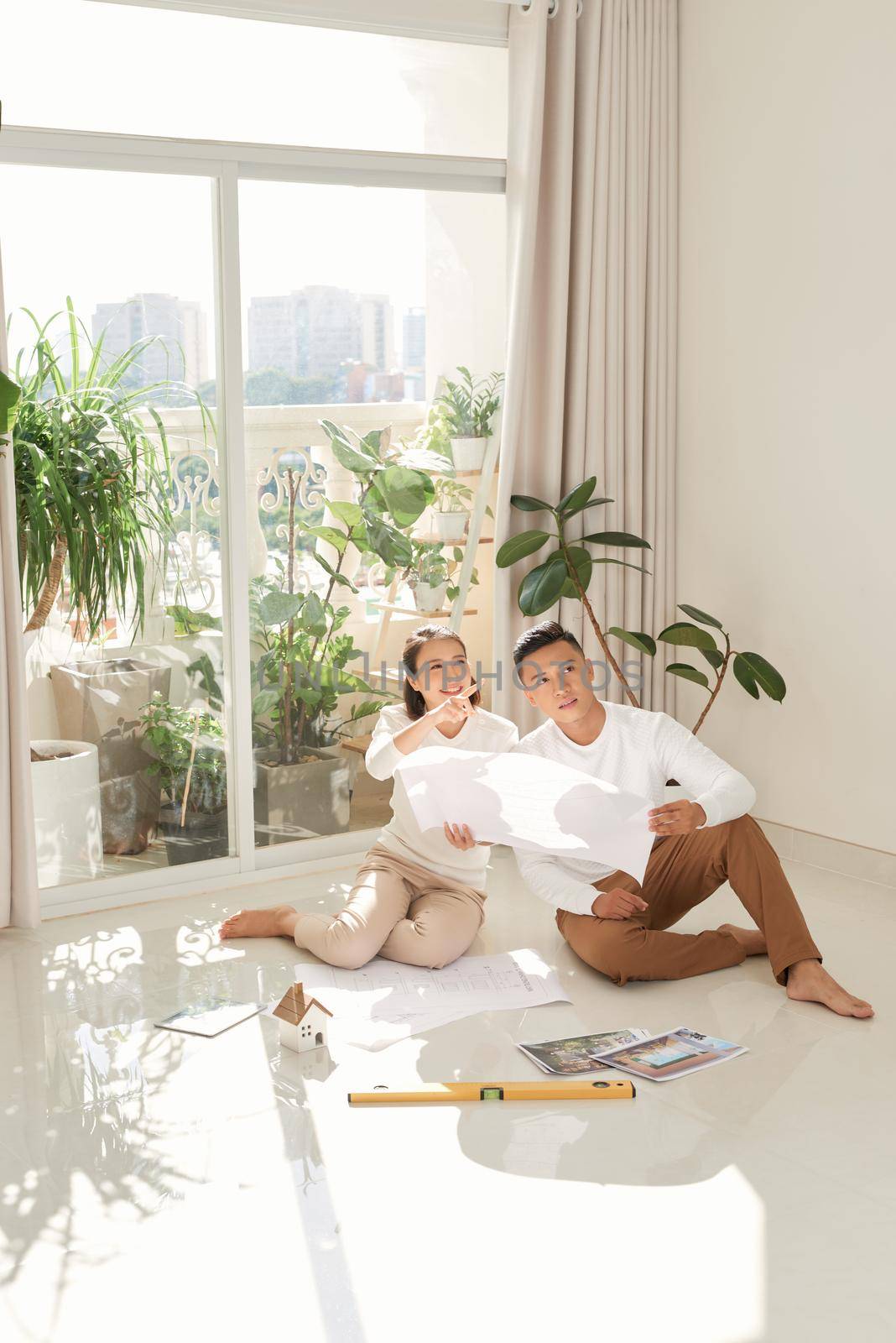 Man and woman looking at their house plans sitting in their new house by makidotvn