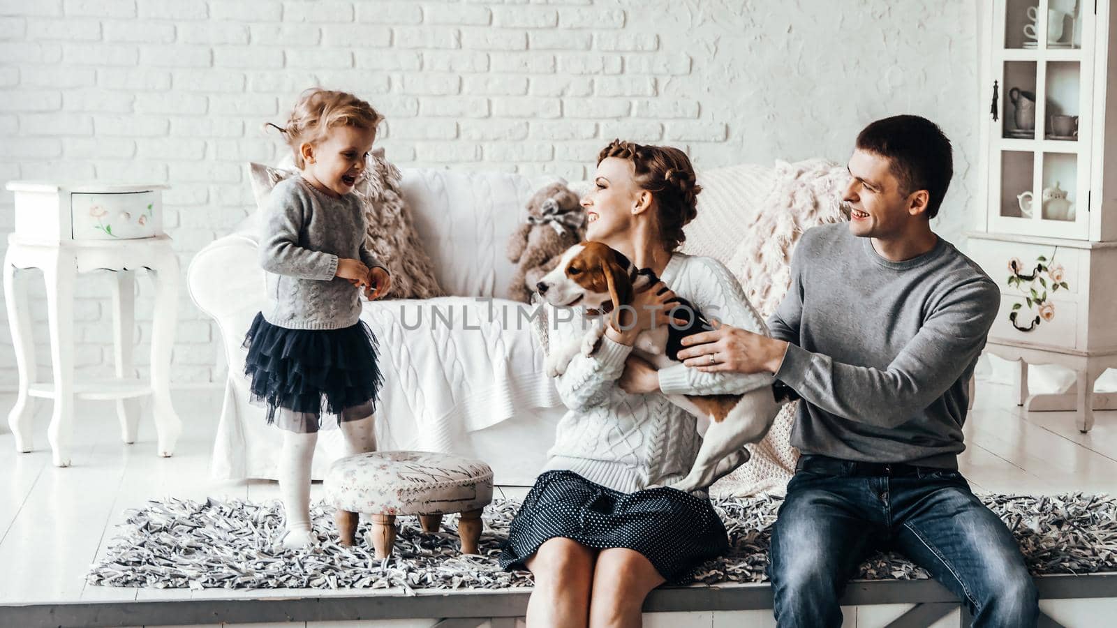 happy parents with five-year-old daughter and their pet dog in the cosy living room