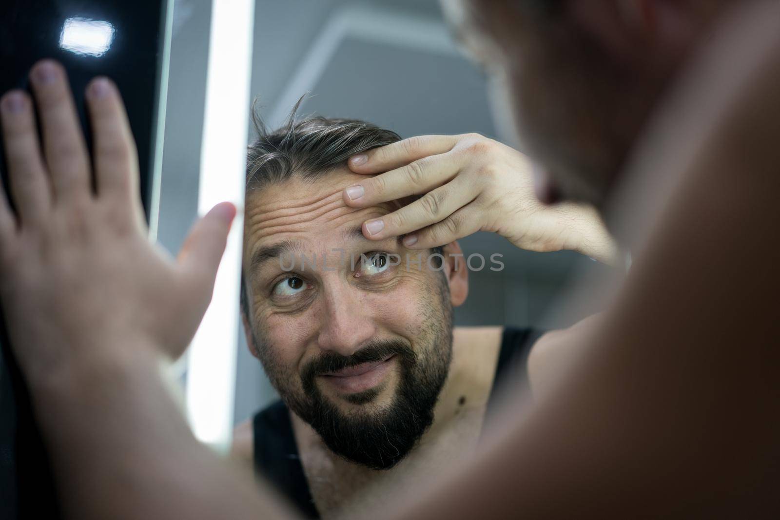Man in front of mirror checking hair and skin