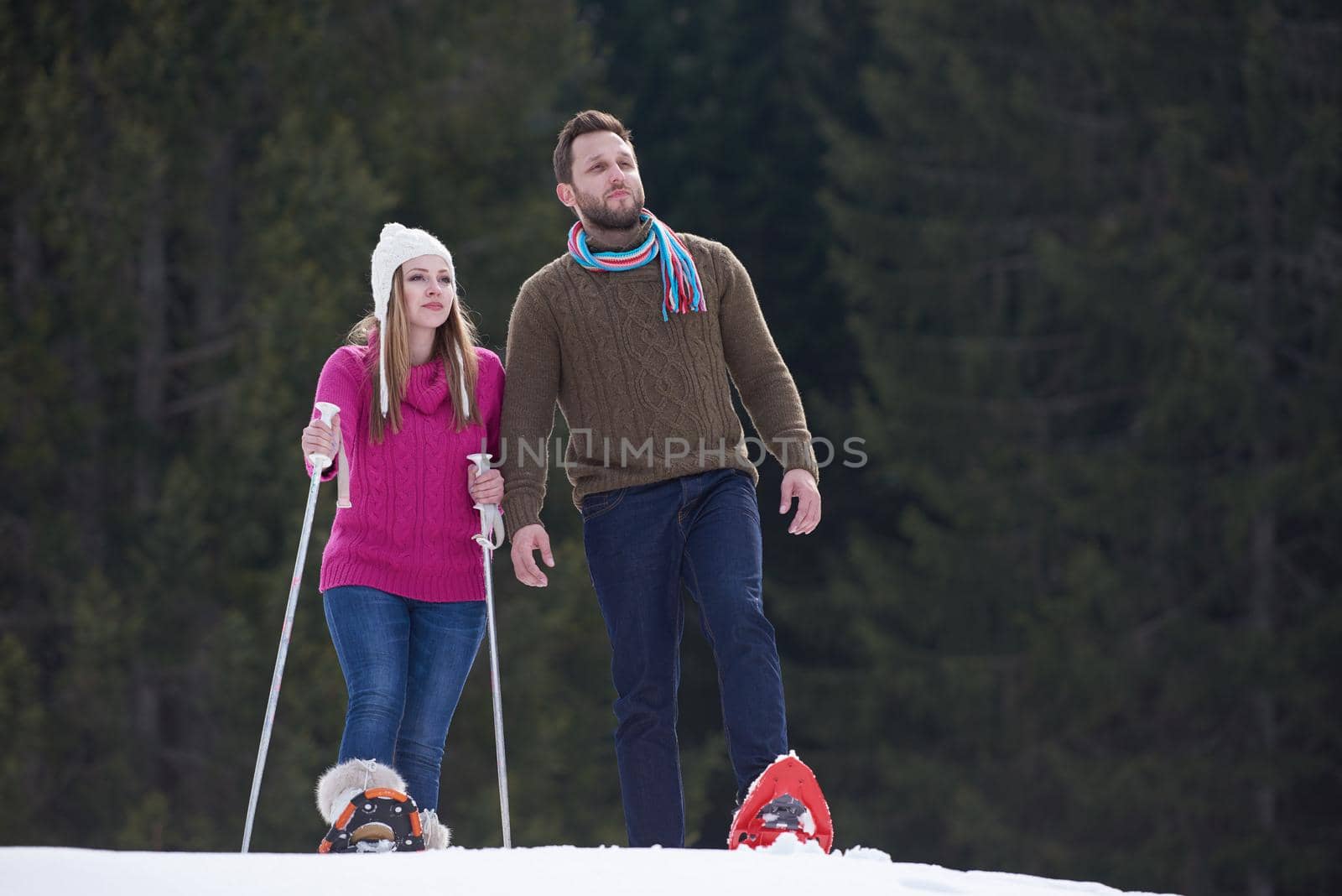 happy young  couple having fun and walking in snow shoes outdoor in nature at beautiful winter day. Health sport and relaxation