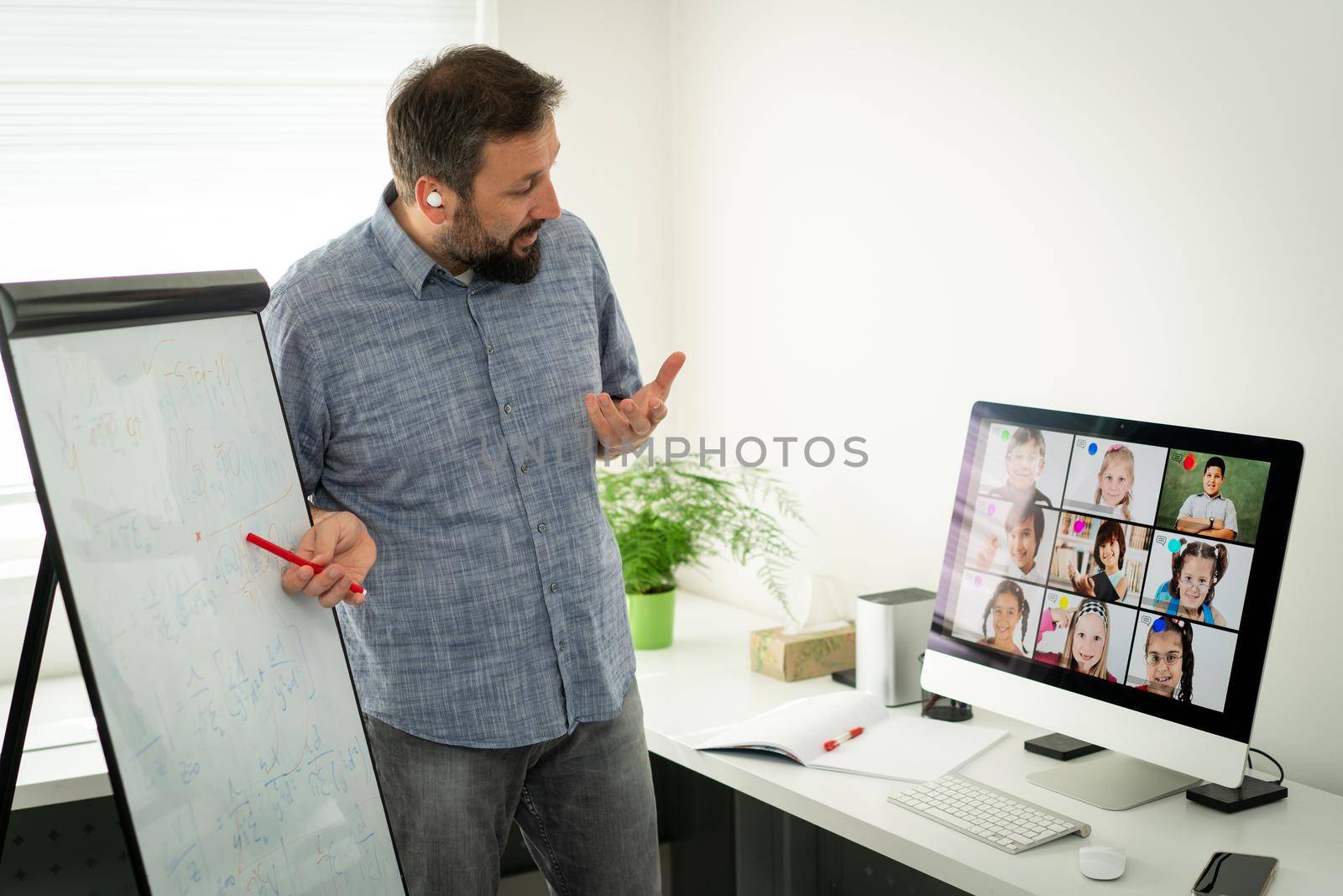 Male teacher having online conference with school children by Zurijeta