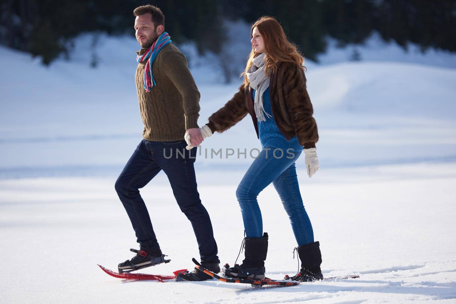 happy young  couple having fun and walking in snow shoes. Romantic winter relaxation scene