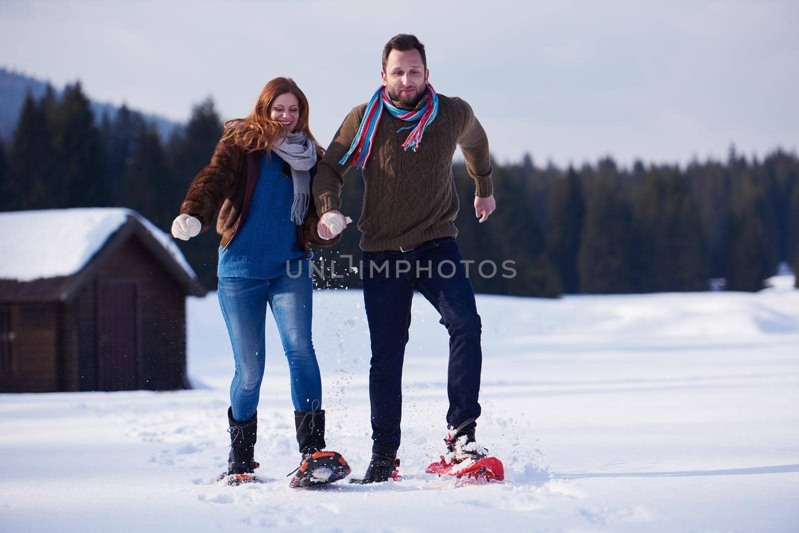 happy young  couple having fun and walking in snow shoes. Romantic winter relaxation scene