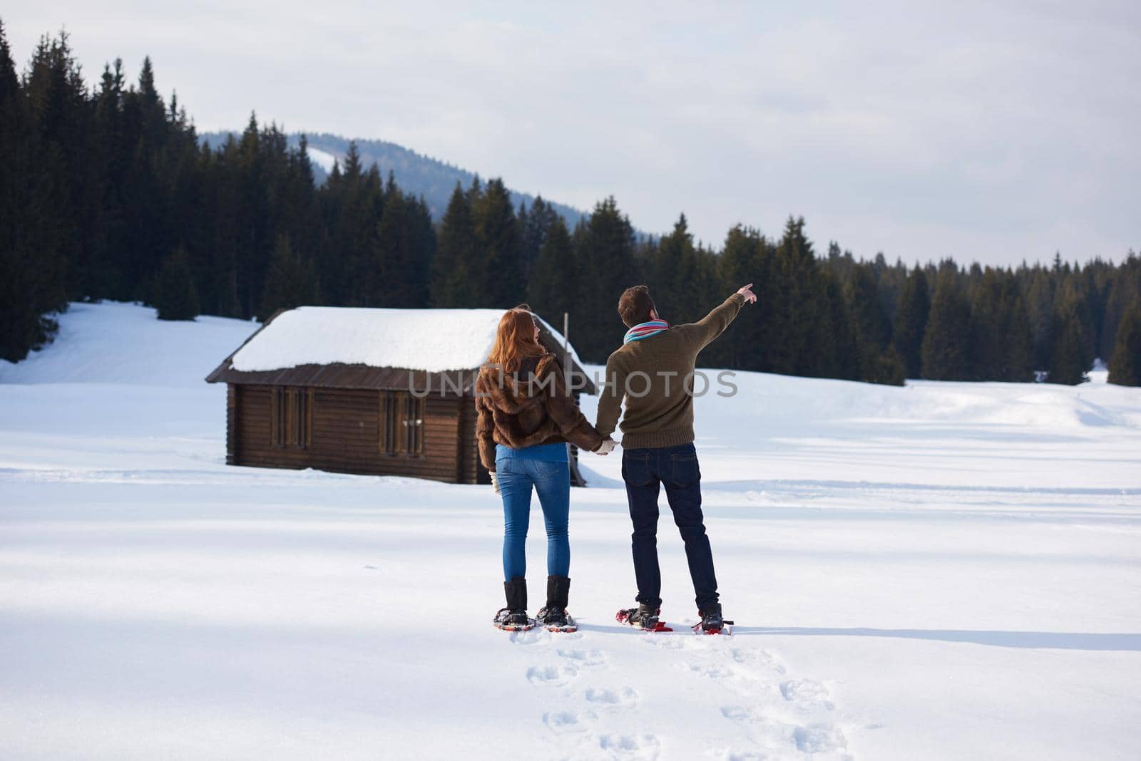 happy young  couple having fun and walking in snow shoes. Romantic winter relaxation scene