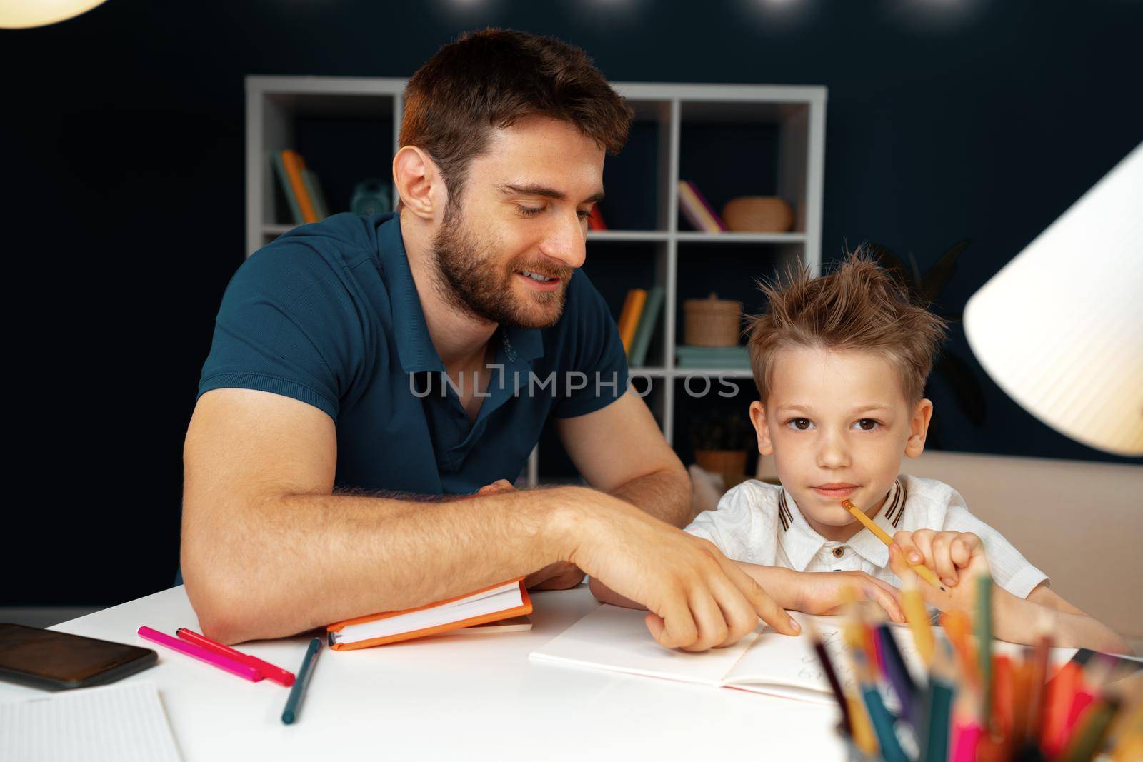 Father helping his little son with school homework close up