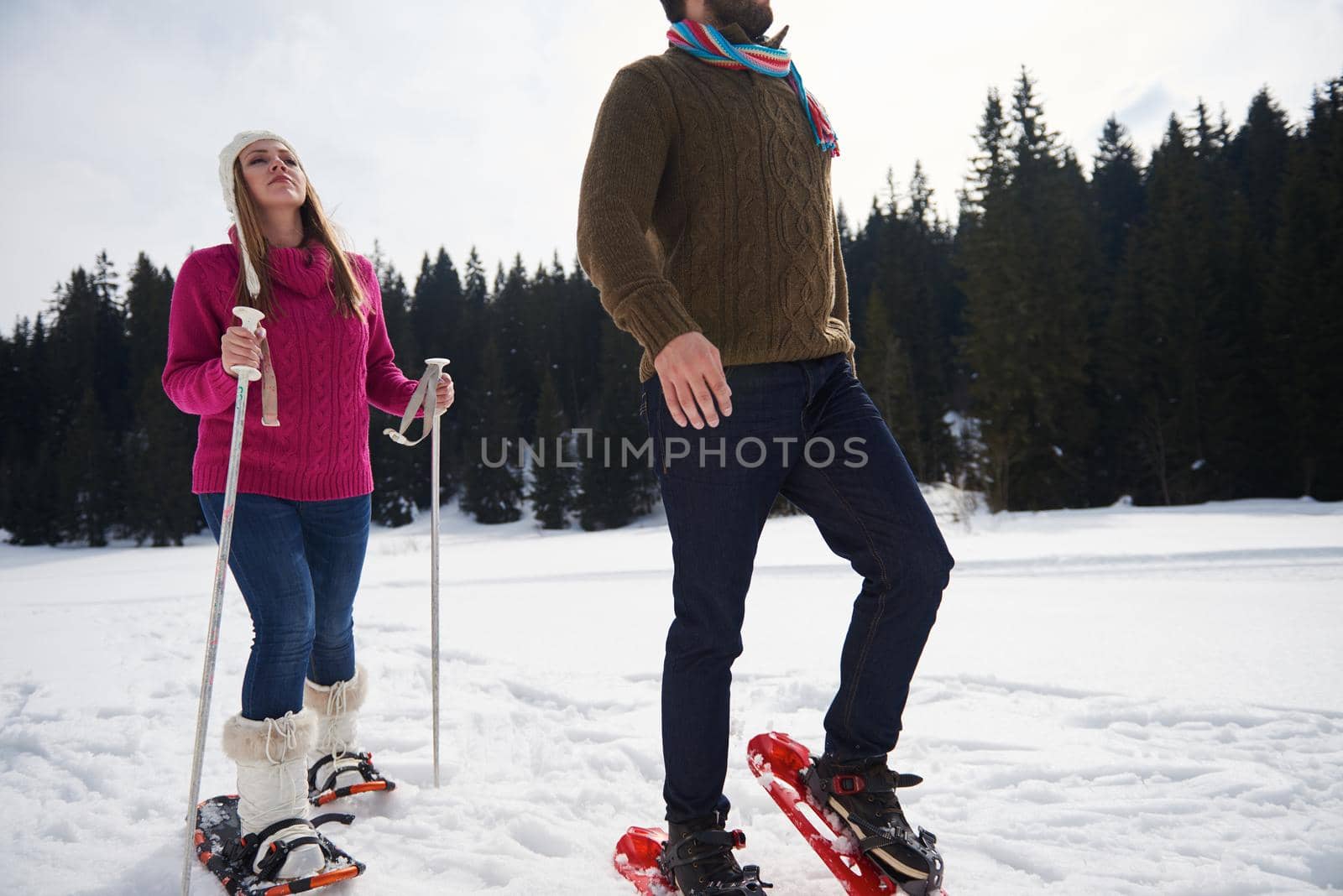 happy young  couple having fun and walking in snow shoes outdoor in nature at beautiful winter day. Health sport and relaxation