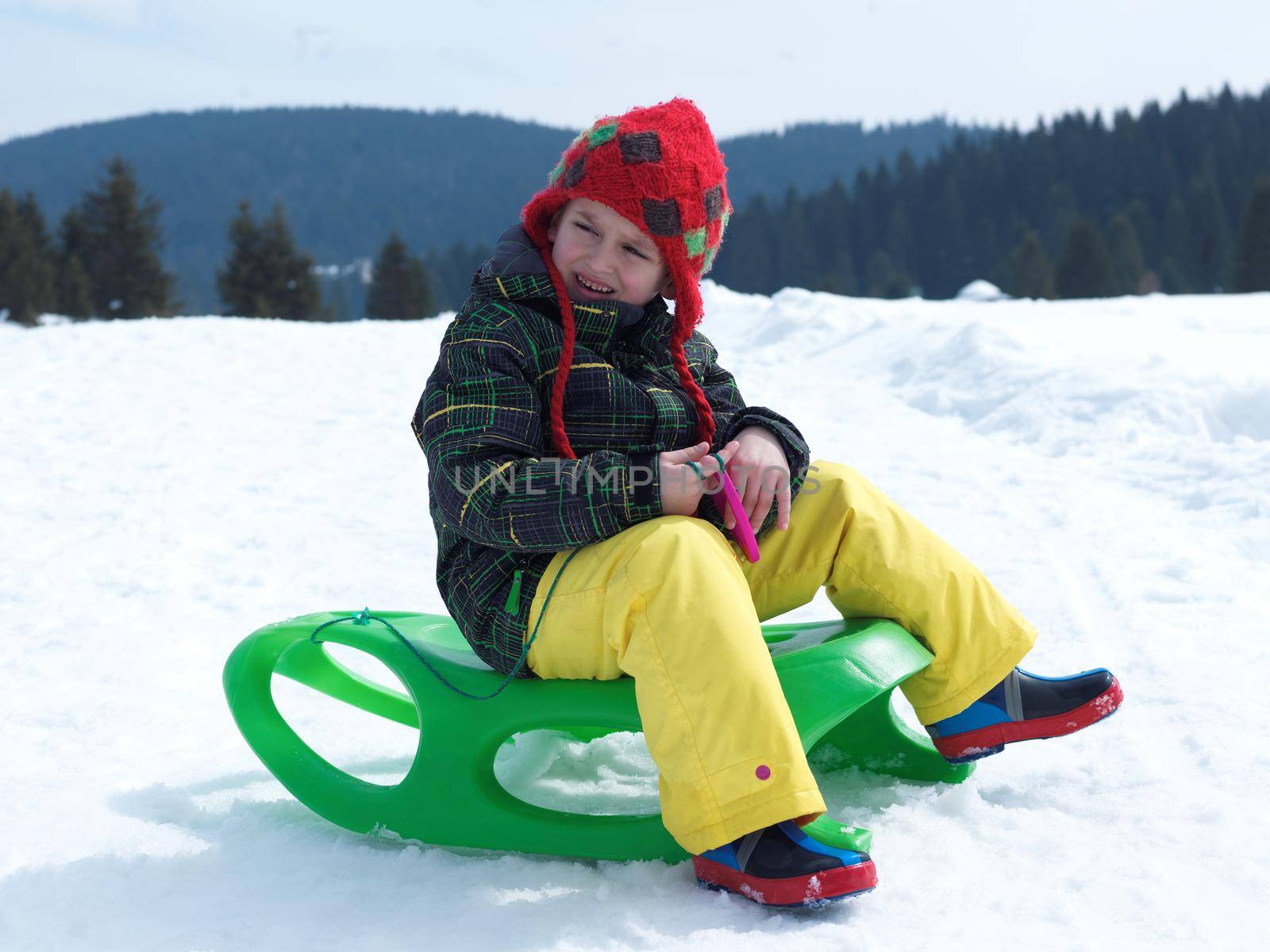 happy young boy have fun on winter vacatioin, sledding children on fresh snow at sunny day outdoor in nature