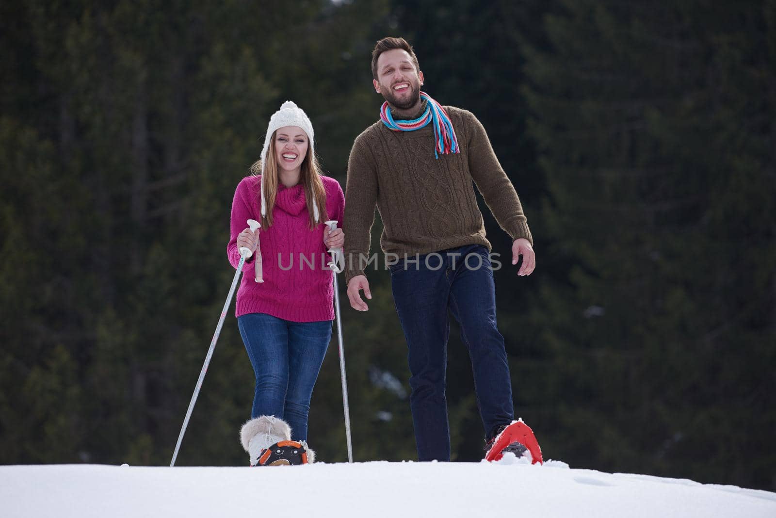 happy young  couple having fun and walking in snow shoes outdoor in nature at beautiful winter day. Health sport and relaxation