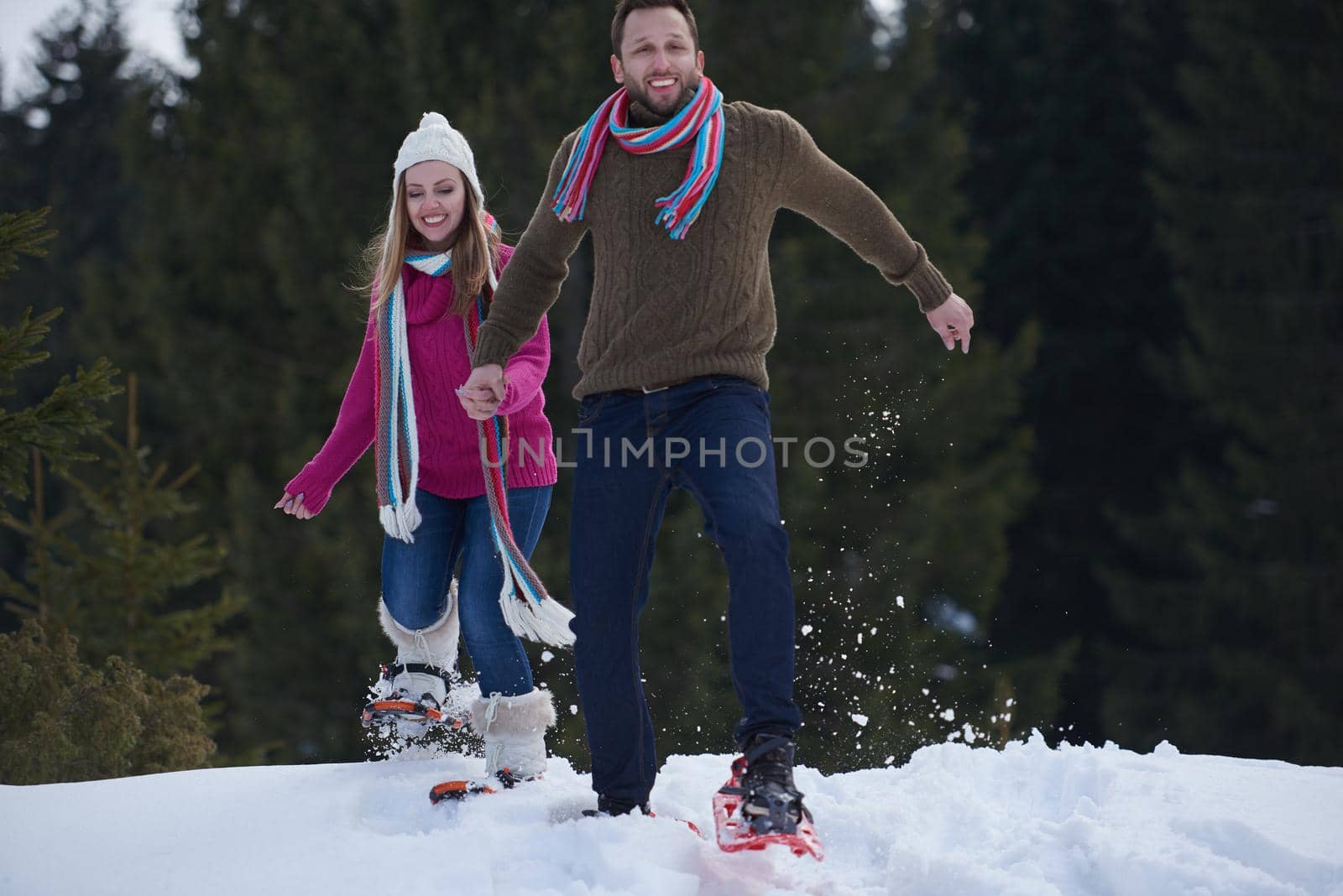 happy young  couple having fun and walking in snow shoes. Romantic winter relaxation scene