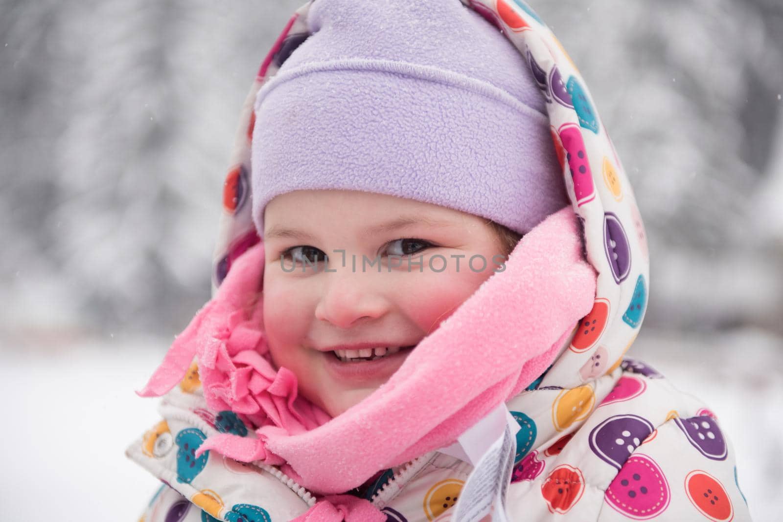 portrait of happy smiling little girl outdoors, having fun and playing on fresh snow on snowy  winter day